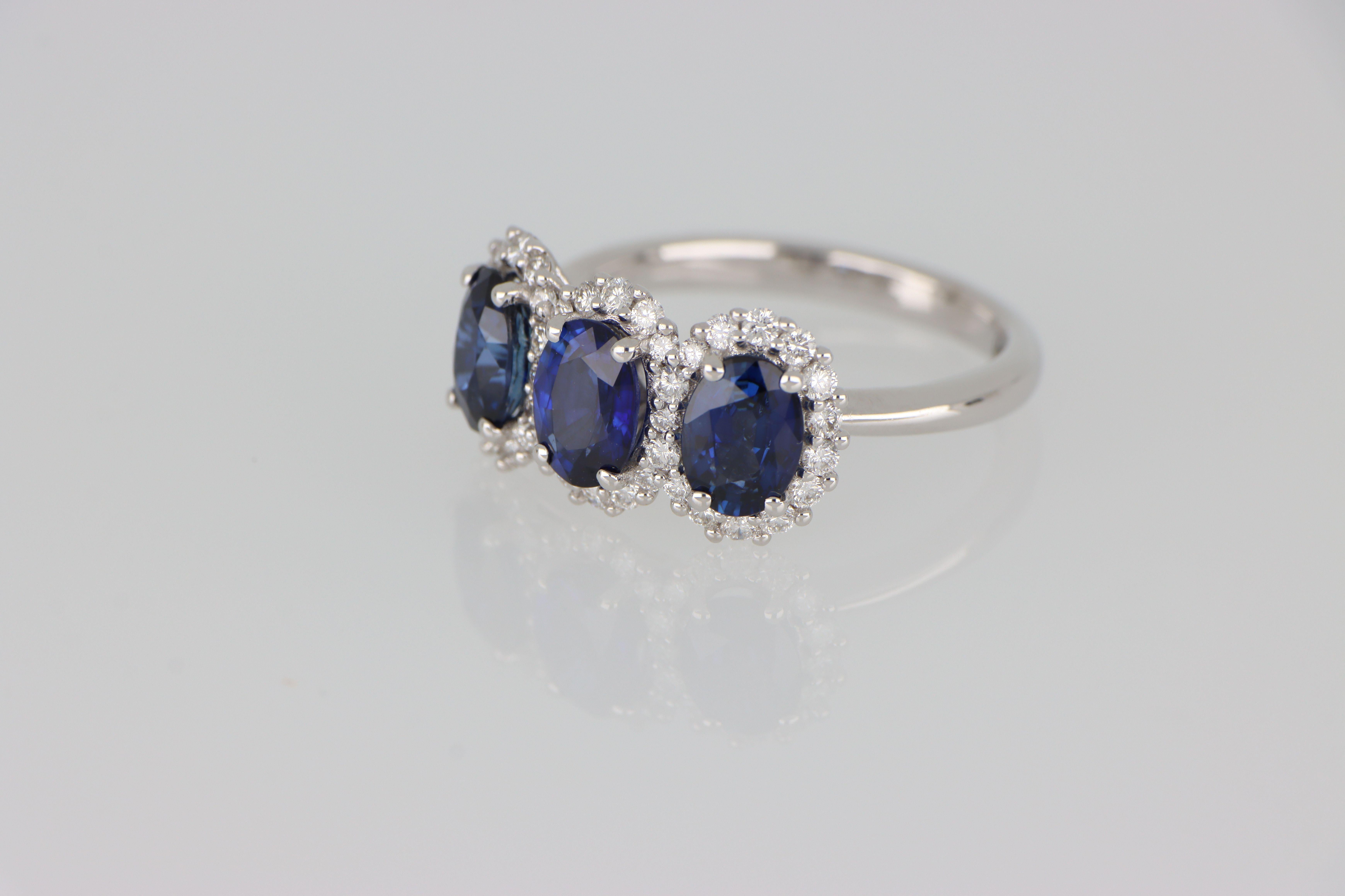 Un raffinato anello in oro bianco 18 kt impreziosito da tre zaffiri ovali naturali (5 × 7 mm, tot. 2,97 ct), circondati da un delicato contorno continuo di diamanti (0,56 ct) a esaltare la luminosità delle gemme. 

Il design rétro emana un fascino