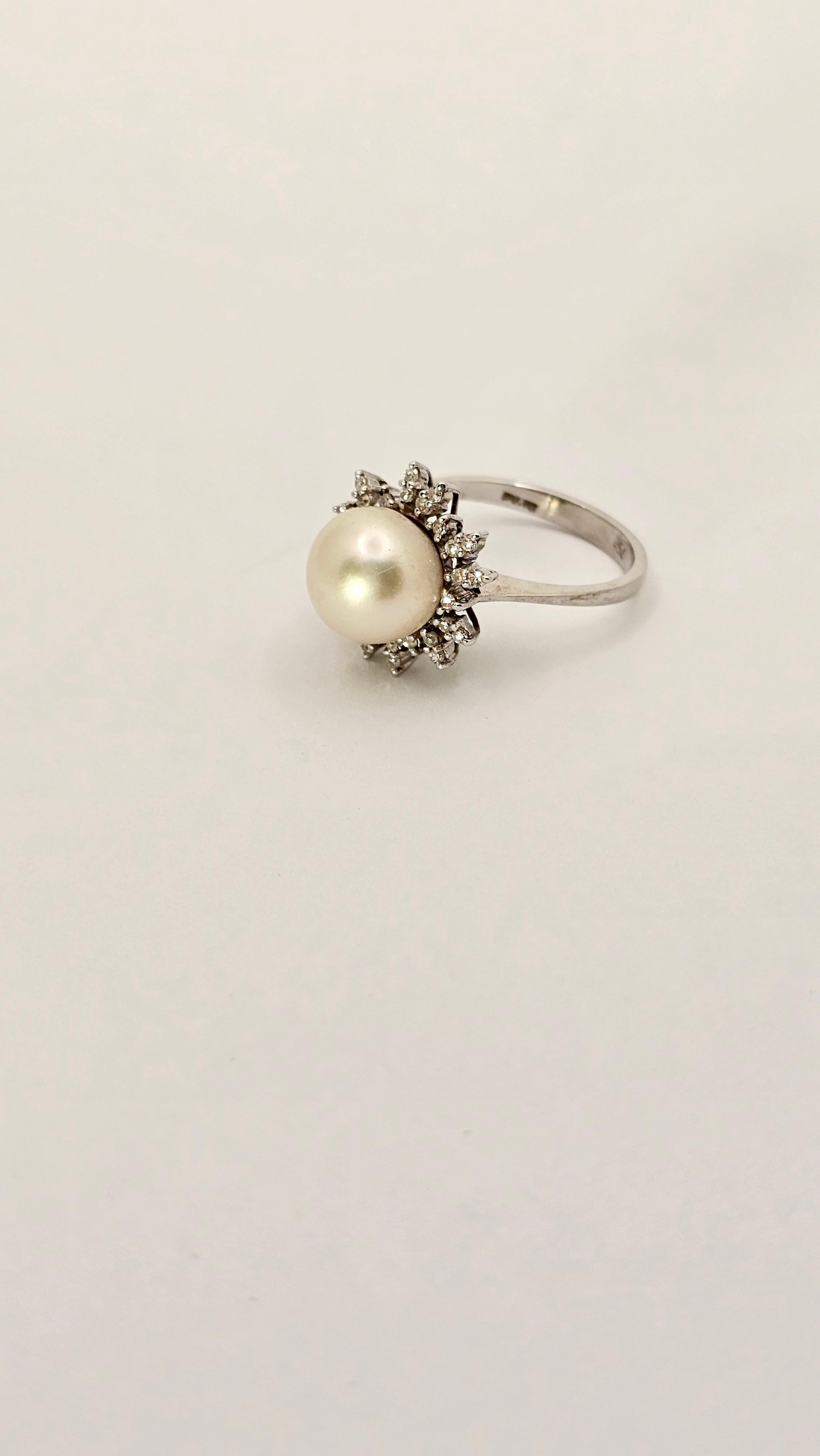 A vintage, 1950s-era ring made of 18 kt white gold weighing 4.80 grams.
The design of this jewelry is typical of its era, the Diamonds are arranged in a frame so as to further bring out all the reflections of the pearl.
The central part has a