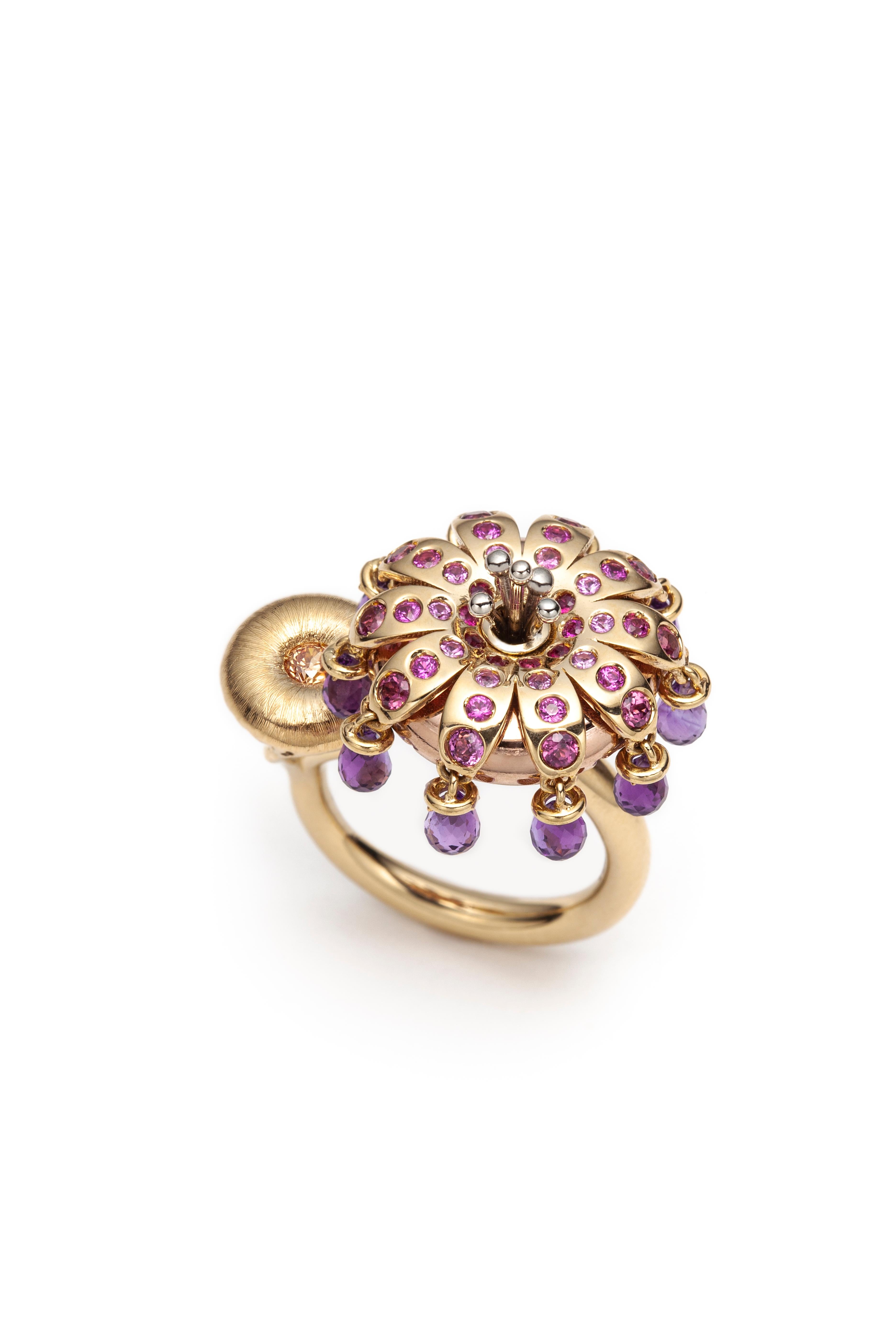 This kinetic ring designed by Lorenzo Serafino, is handcrafted from 18K yellow, pink and white gold and set with pink sapphire and yellow tourmaline. Briolette cut Amethysts hang from the freely rotating flower on the top of the ring.

—What do you