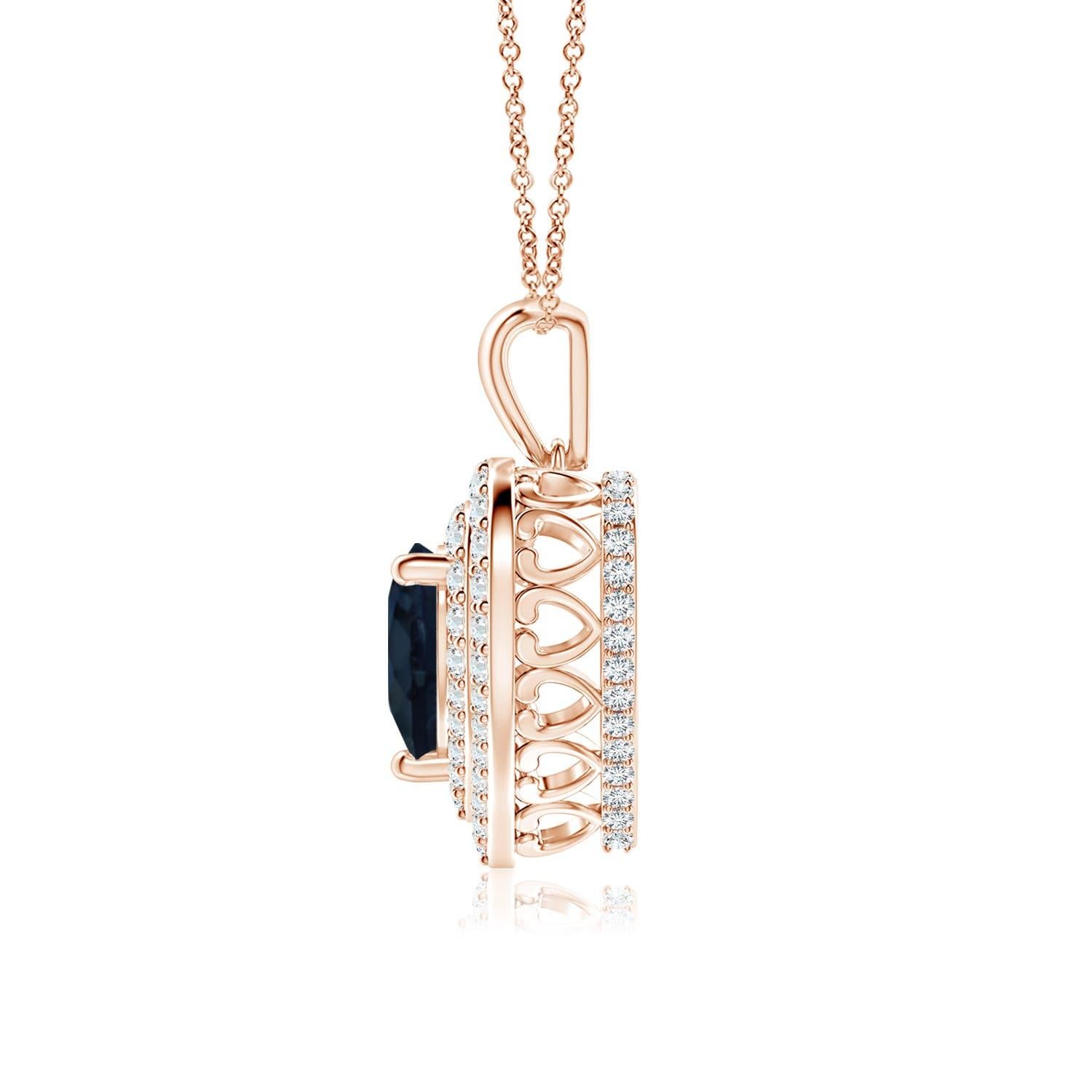 Un saphir bleu en forme de cœur est entouré d'un double halo serti de diamants rayonnants dans un serti clos. Un motif en forme de cœur incrusté de diamants relie la balle en métal au cadre en forme de cœur. Les diamants étincelants créent un