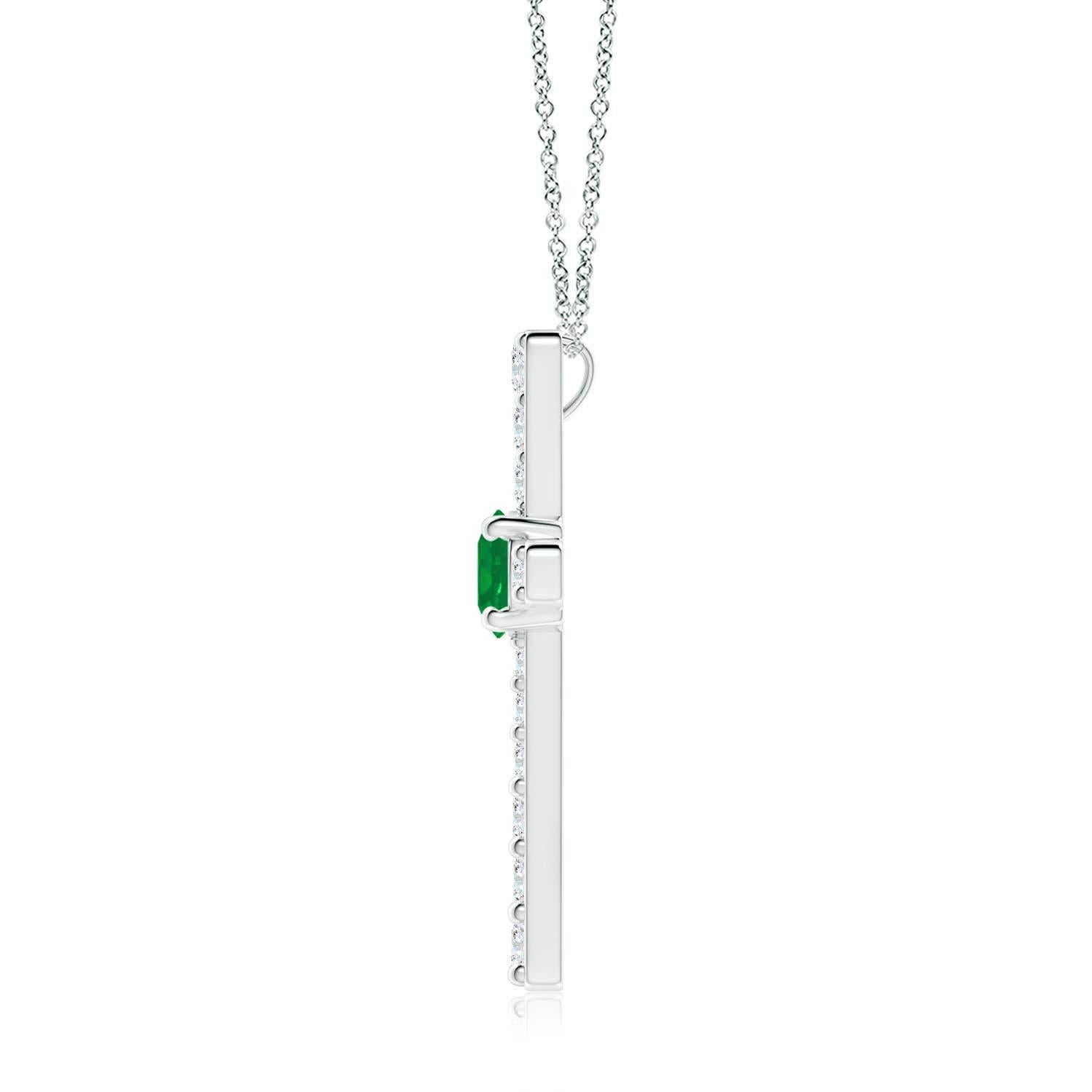 Ce pendentif en forme de croix réalisé en or blanc 14k est une splendide expression de votre foi. Elle est ornée de diamants ronds sertis sur la tranche et d'une émeraude verte luxuriante en son centre, ce qui crée un magnifique