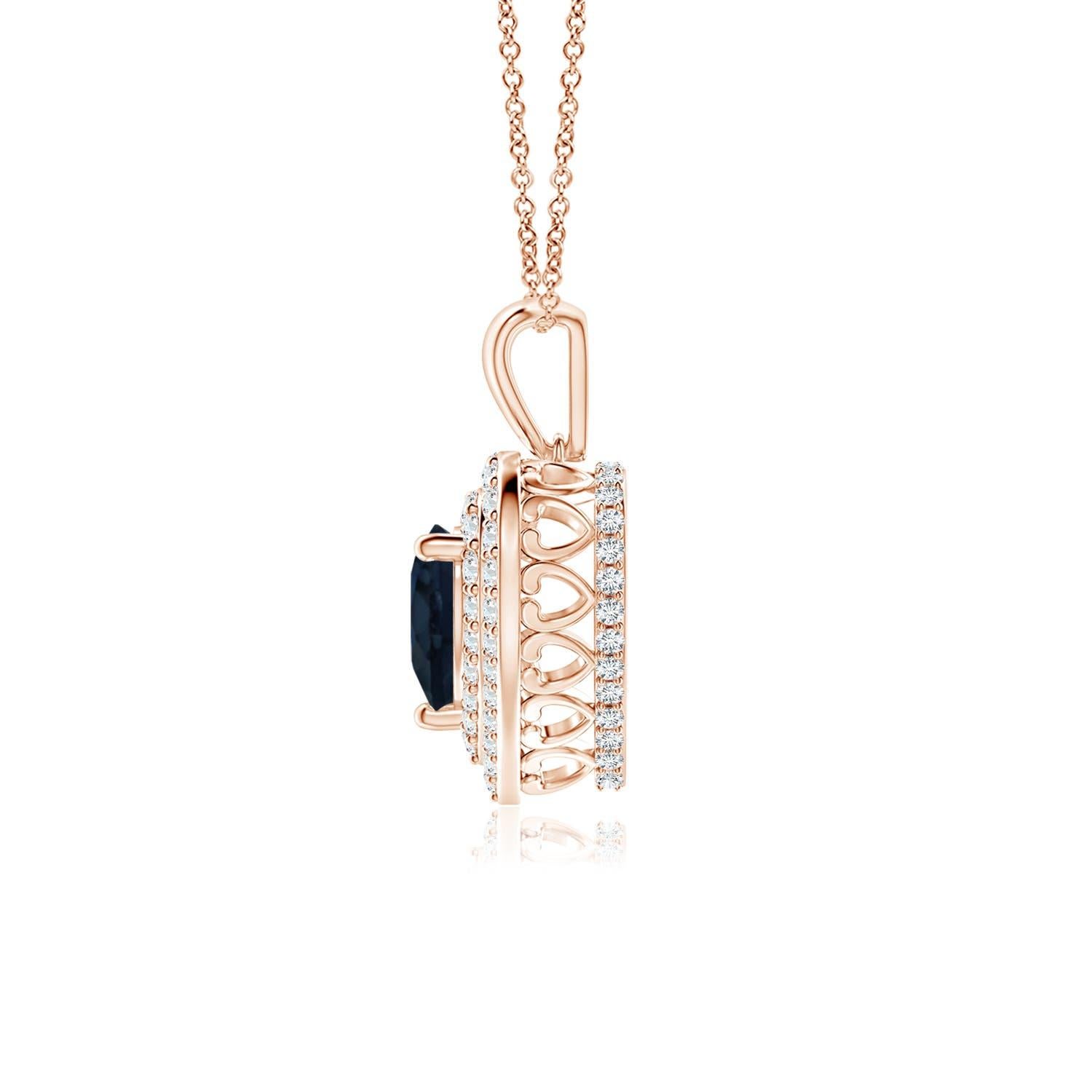 Un saphir bleu en forme de cœur est entouré d'un double halo serti de diamants rayonnants dans un serti clos. Un motif en forme de cœur incrusté de diamants relie la balle en métal au cadre en forme de cœur. Les diamants étincelants créent un