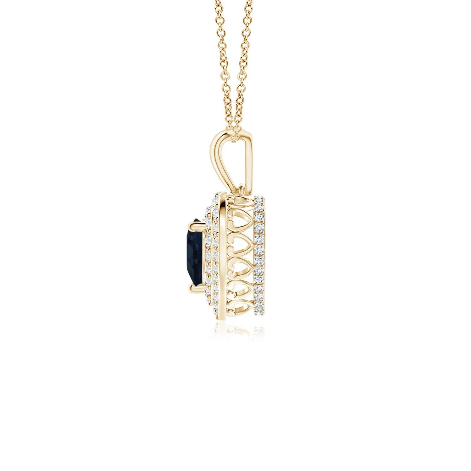Un saphir bleu en forme de cœur est entouré d'un double halo serti de diamants rayonnants dans un serti clos. Un motif en forme de cœur incrusté de diamants relie la balle en métal au cadre en forme de cœur. Les diamants étincelants créent un
