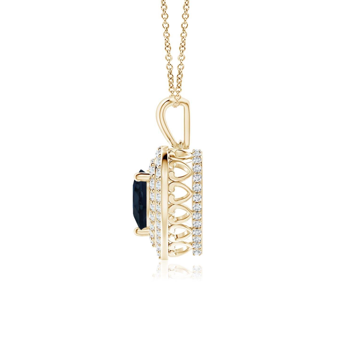 Un saphir bleu en forme de cœur est entouré d'un double halo serti de diamants rayonnants dans une monture à griffes. Un motif en forme de cœur incrusté de diamants relie la balle en métal au cadre en forme de cœur. Les diamants étincelants créent