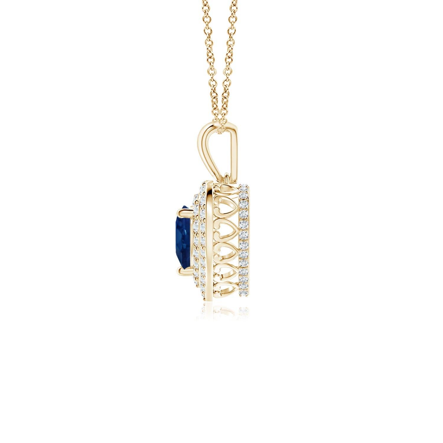 Un saphir bleu en forme de cœur est entouré d'un double halo serti de diamants rayonnants dans un serti clos. Un motif en forme de cœur incrusté de diamants relie la balle en métal au cadre en forme de cœur. Les diamants étincelants créent un