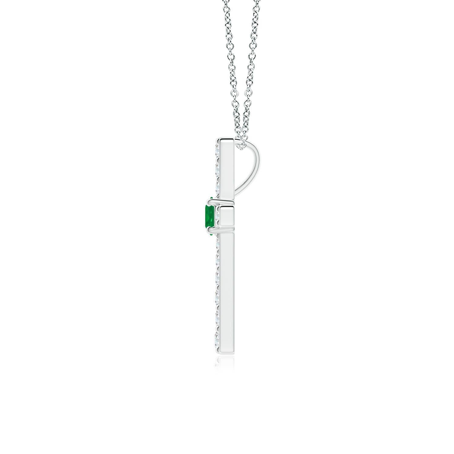 Ce pendentif en forme de croix réalisé en or blanc 14k est une splendide expression de votre foi. Elle est ornée de diamants ronds sertis sur la tranche et d'une émeraude verte luxuriante en son centre, ce qui crée un magnifique