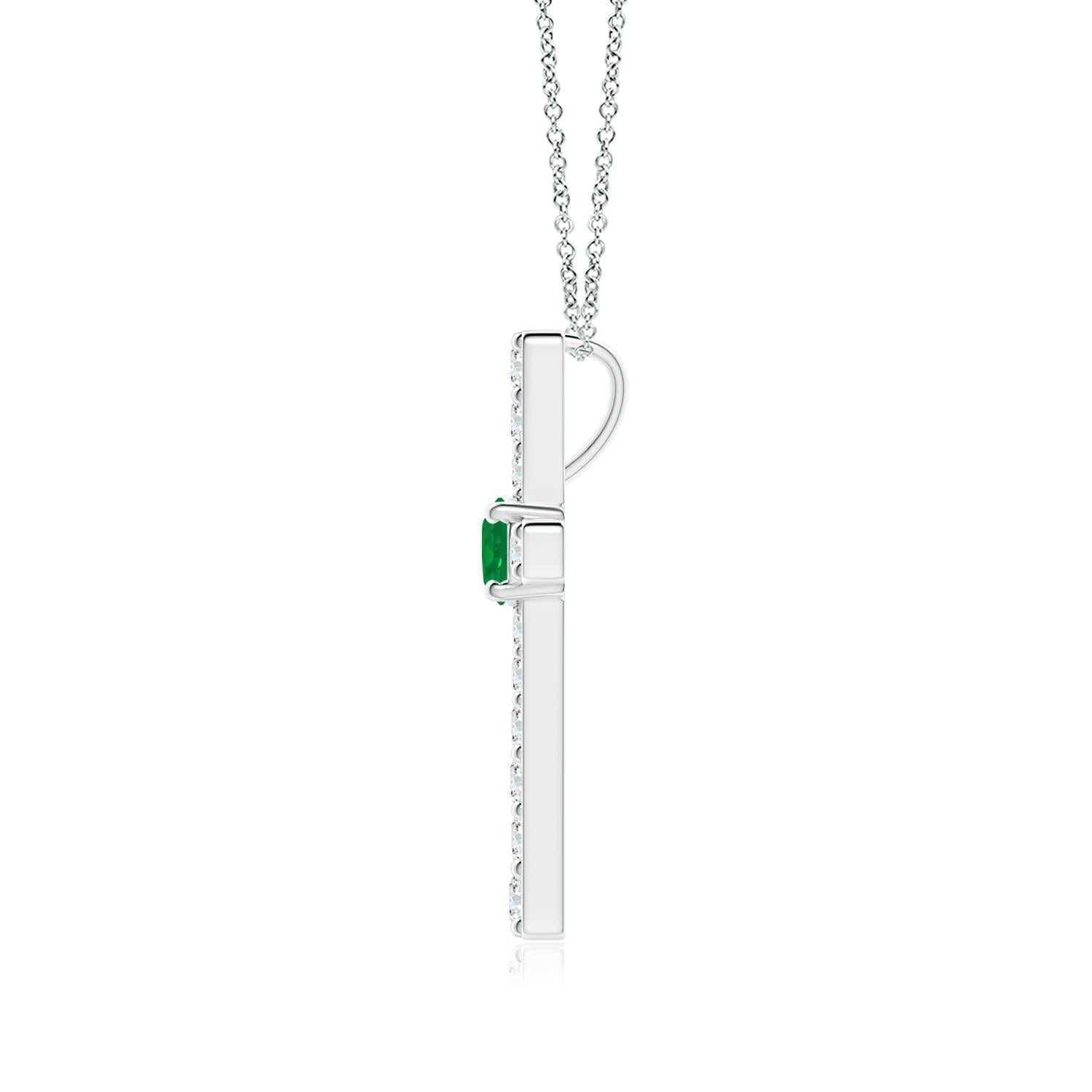 Ce pendentif en forme de croix réalisé en or blanc 14k est une splendide expression de votre foi. Elle est ornée de diamants ronds sertis sur la tranche et d'une émeraude verte luxuriante en son centre, ce qui crée un magnifique