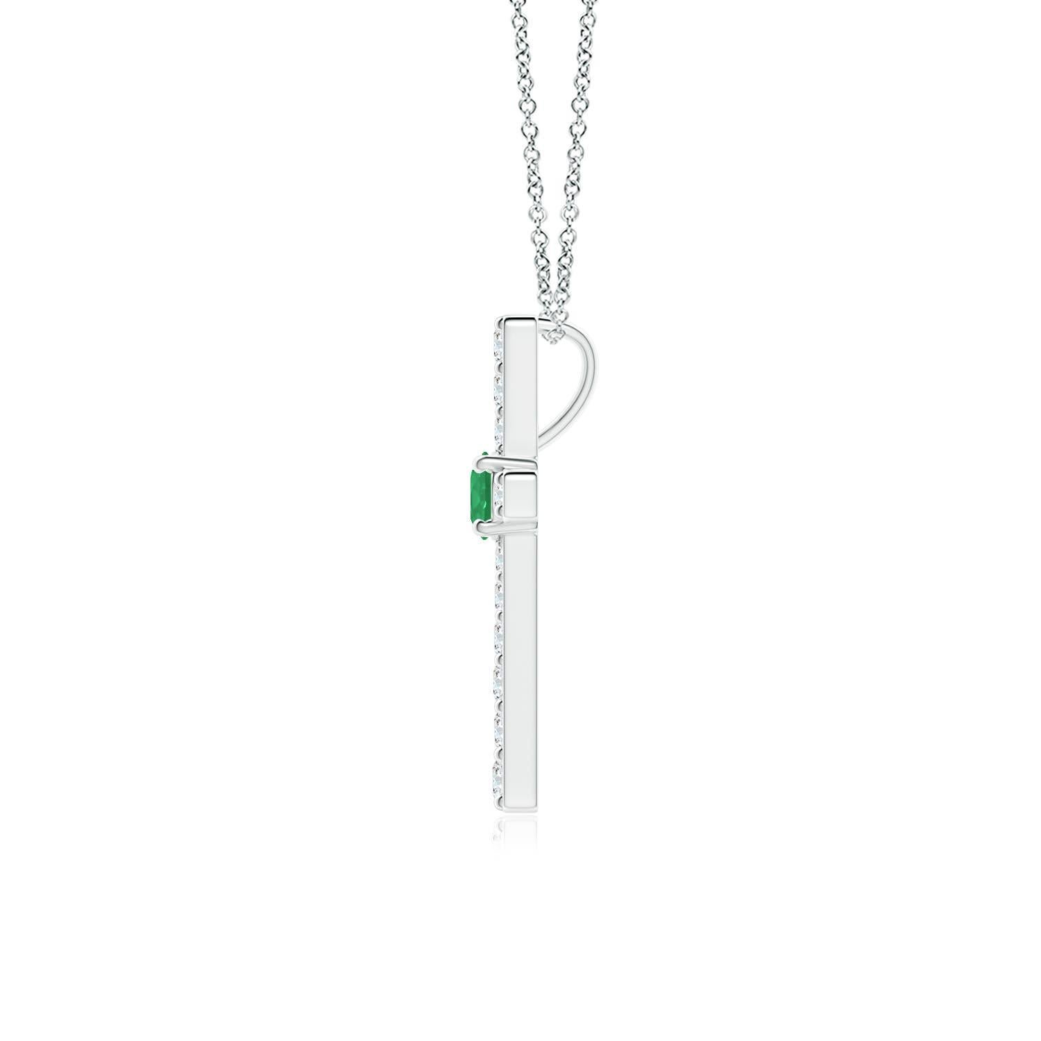 Ce pendentif en forme de croix réalisé en or blanc 14k est une splendide expression de votre foi. Elle est ornée de diamants ronds sertis sur la tranche et d'une émeraude verte luxuriante en son centre, ce qui crée un magnifique