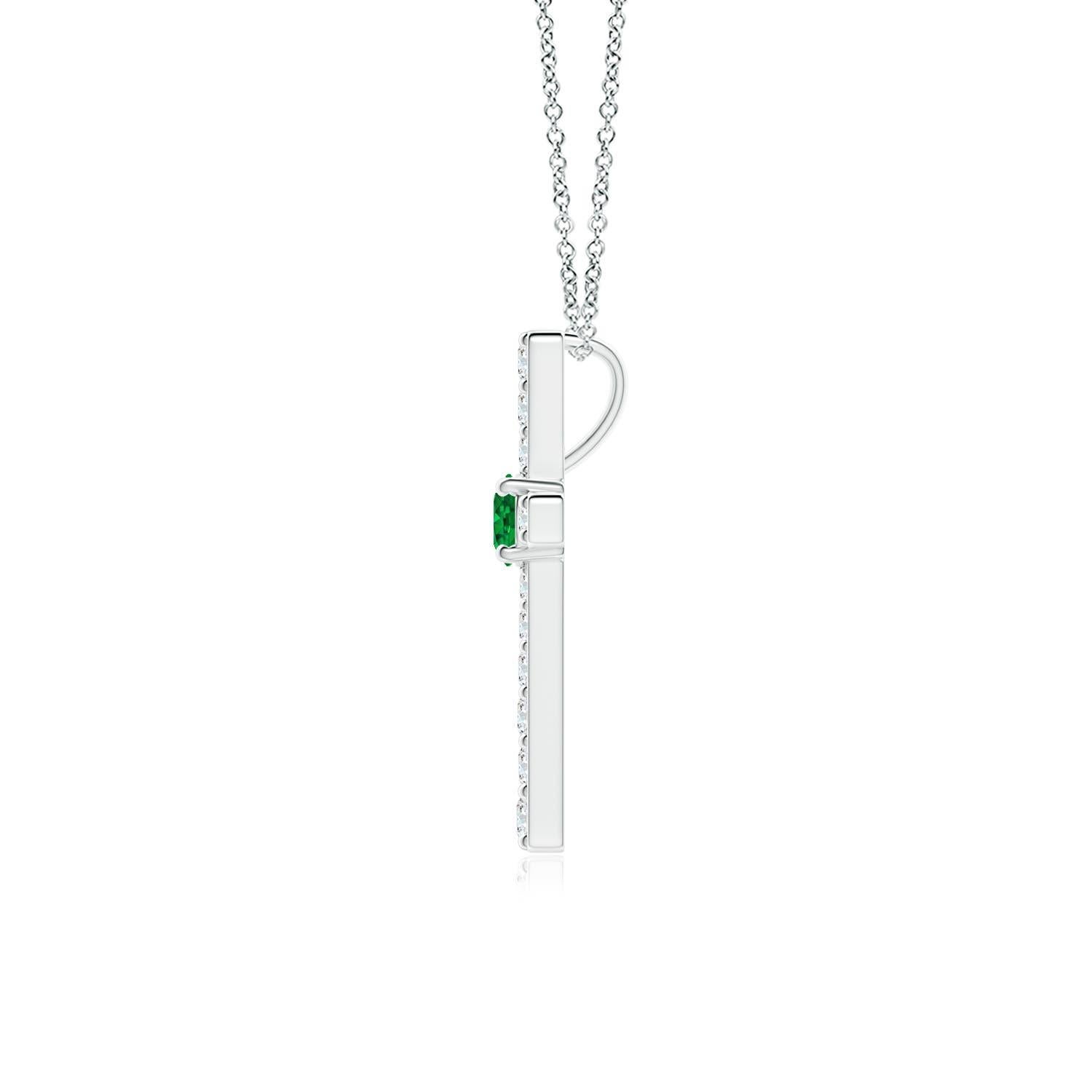 Ce pendentif en forme de croix réalisé en or blanc 14k est une splendide expression de votre foi. Elle est ornée de diamants ronds sertis sur la tranche et d'une émeraude verte luxuriante en son centre, ce qui crée un magnifique