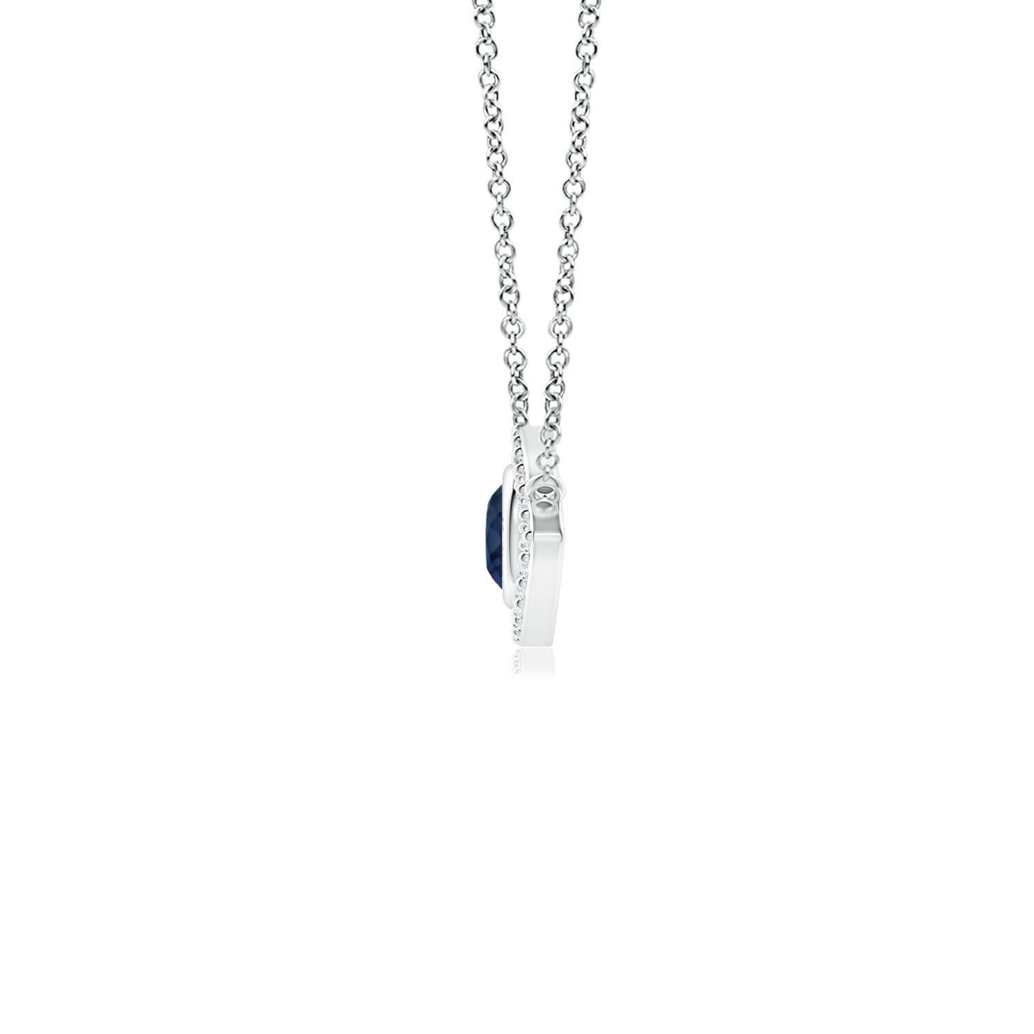 Hanging gracefully from a shiny metal bale is a diamond studded frame with a round sapphire bezel set at the center. The sparkling diamonds create a compelling contrast against the deep blue sapphire. Crafted in 14k white gold, this sapphire evil