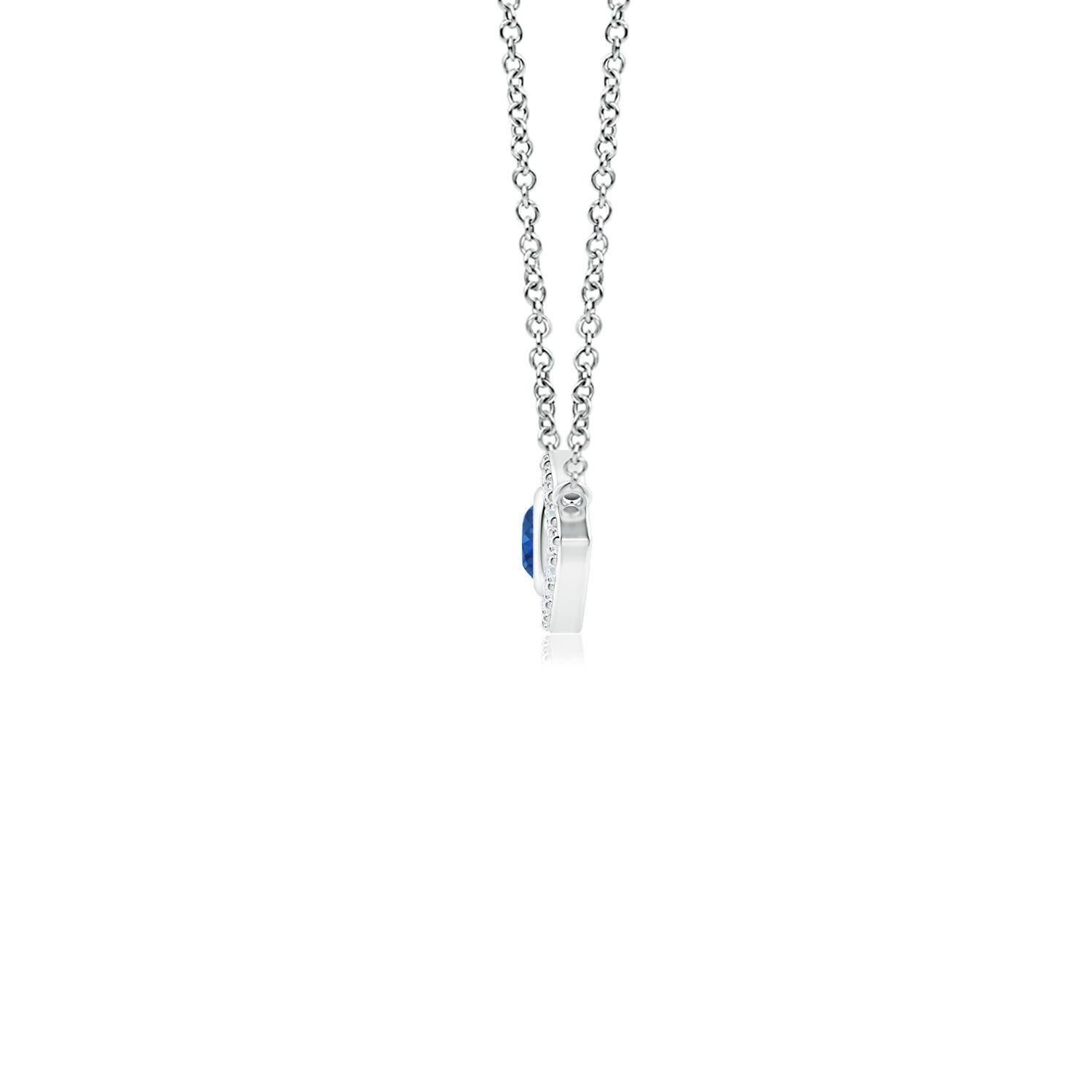 Hanging gracefully from a shiny metal bale is a diamond studded frame with a round sapphire bezel set at the center. The sparkling diamonds create a compelling contrast against the deep blue sapphire. Crafted in 14k white gold, this sapphire evil
