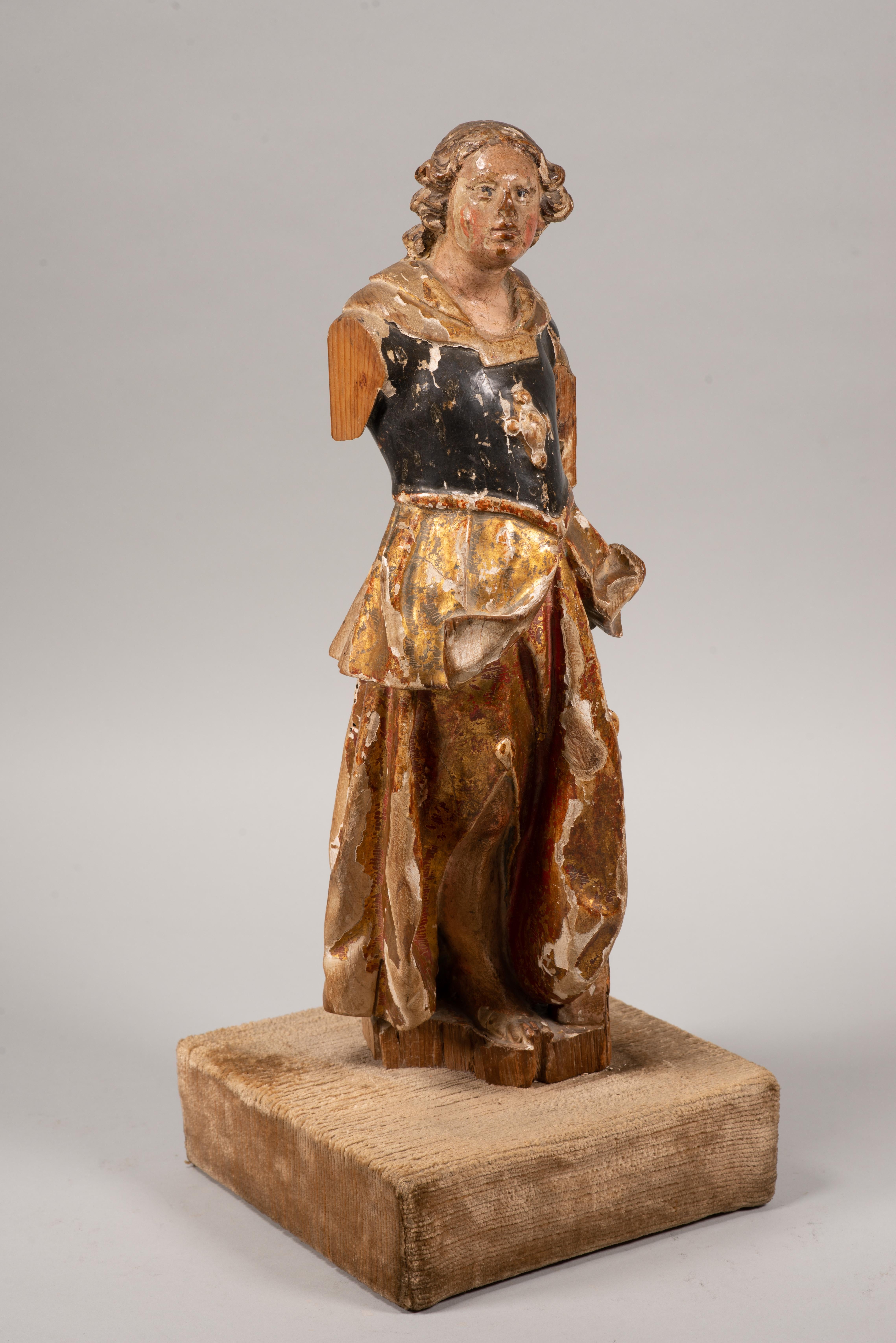  Ange, archange ou saint, sur une base. Bois sculpté et polychrome, textile, etc. Spanish School, XVIIe siècle.
 Il présente des défauts. 
Sculpture en bois sculpté, polychrome et doré représentant un jeune homme vêtu d'une armure rappelant le