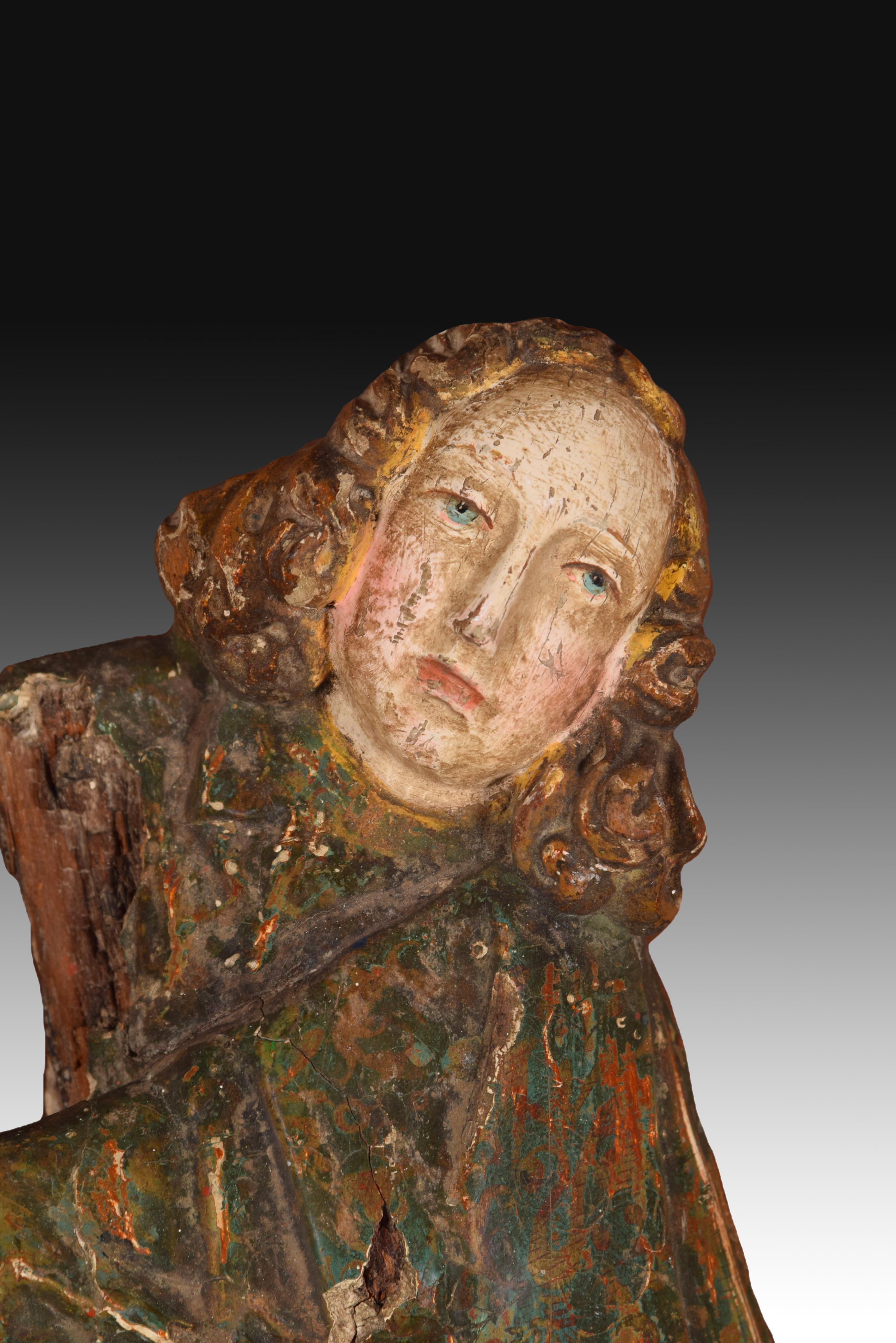 Angel. Carved and polychrome wood. Century XVI. 
 Polychrome wood carving showing an angel, with the face facing the viewer and the body in profile, dressed in a long tunic whose folds curve to one side and cover the entire body of the figure.