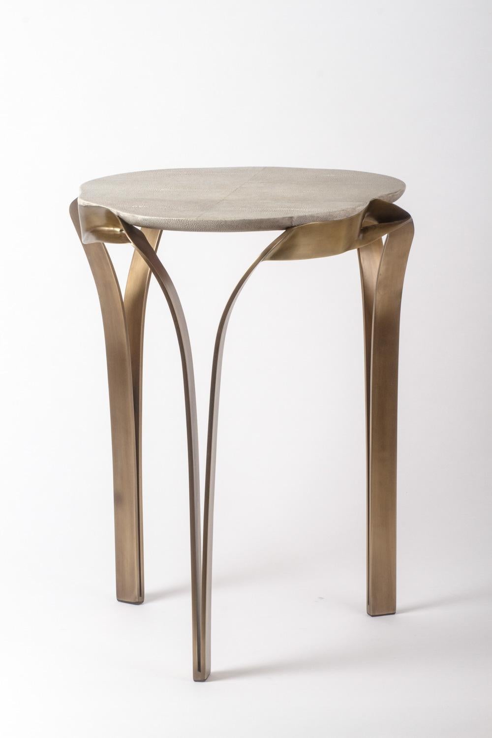 The organic design of the angel falls side table, is inspired by one of the world’s most beautiful waterfalls. The amorphous shaped top in cream shagreen is elegantly wrapped with a bronze-patina brass frame that melts into the table's legs.

The