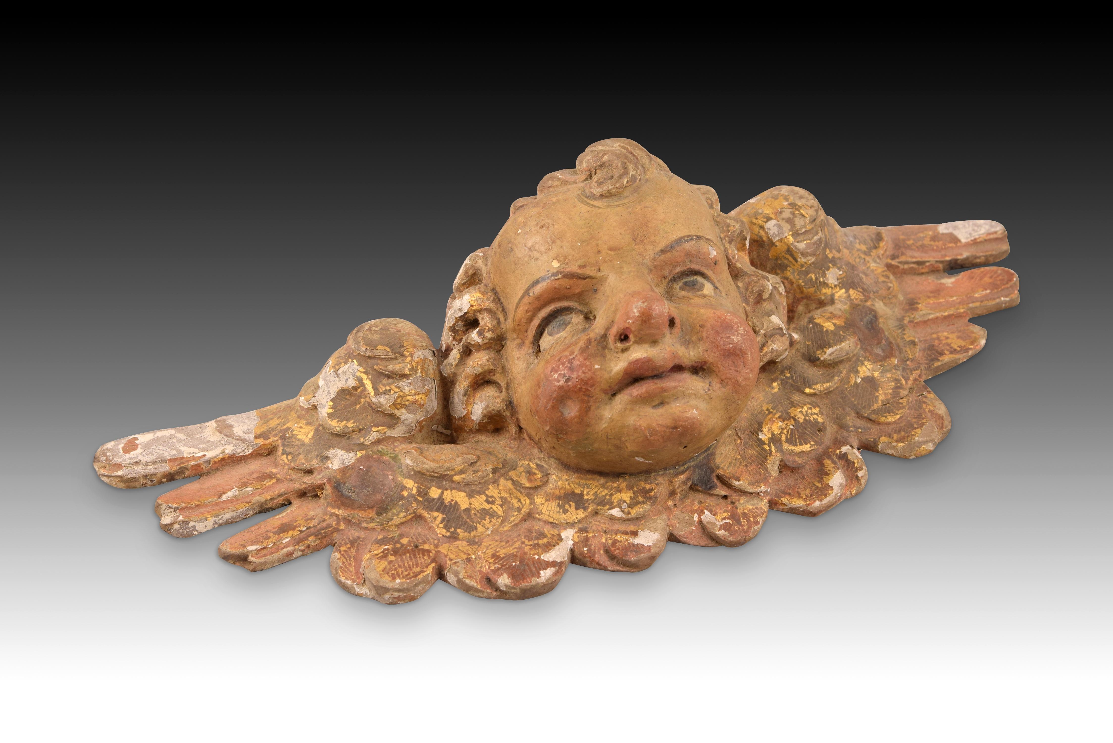 Angel head carved and polychrome wood. XVII century. 
Wood carving with a polychrome finish that shows a child's head with curly hair from which two wings spread to the sides, open and with golden details on the feathers. These types of decorative