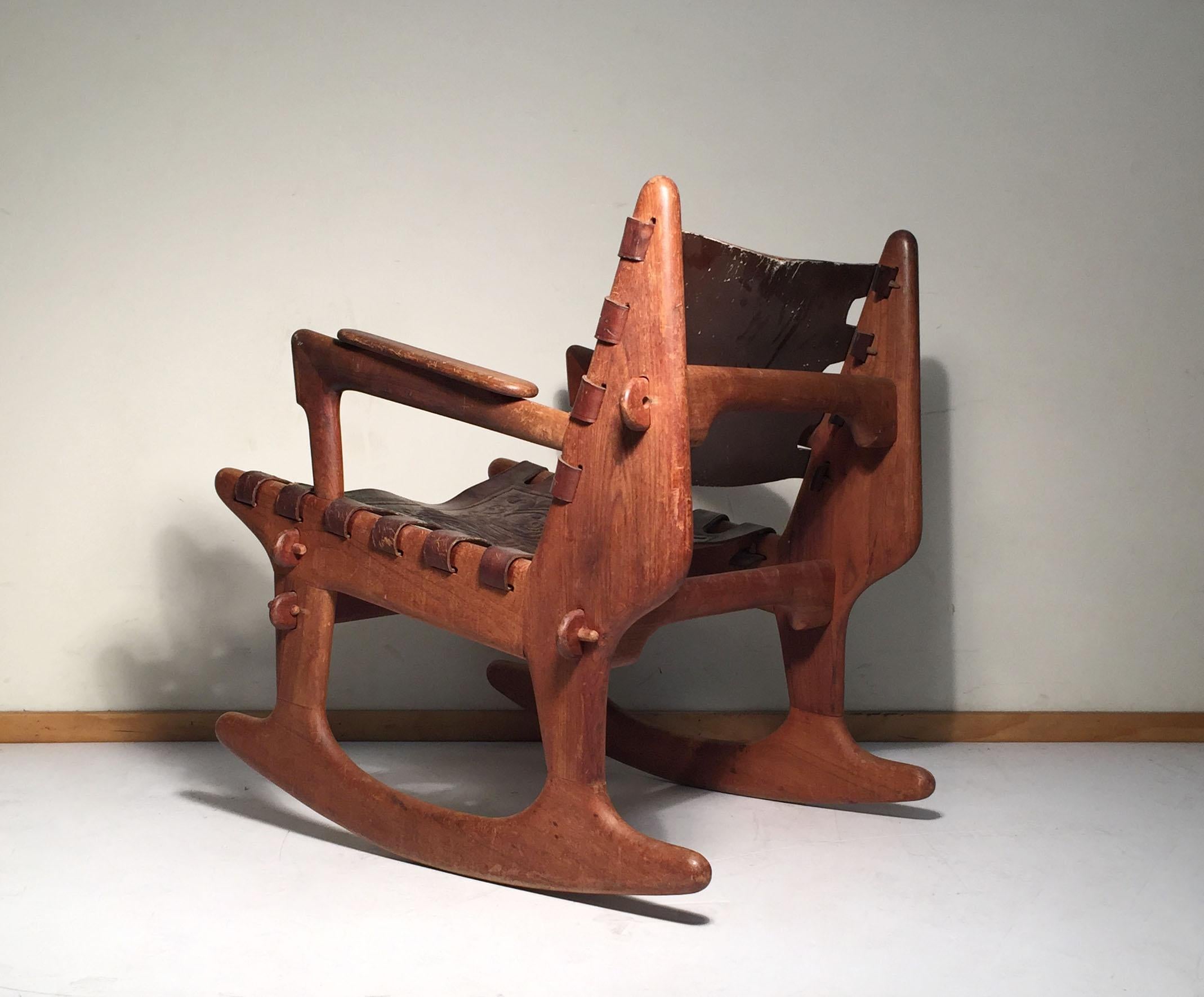 Vintage rocker by Angel Pazmino. Untouched . In original finish with tooled leather backrest and seat. Fully signed.
In the style of Adrian Pearsall.

Can use some oil to just freshen up the wood.