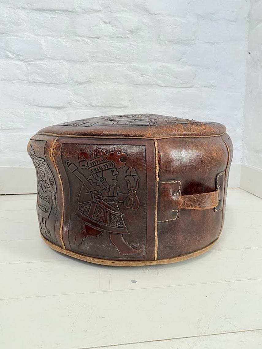 Brown leather low stool round pouf with intricate Mayan motif doubling as a zippered suitcase secret compartment! Central American Mayan relief tooled design attributed to Angel Pazmino. Ecuador 1960s. Unmarked piece. Original unrestored vintage