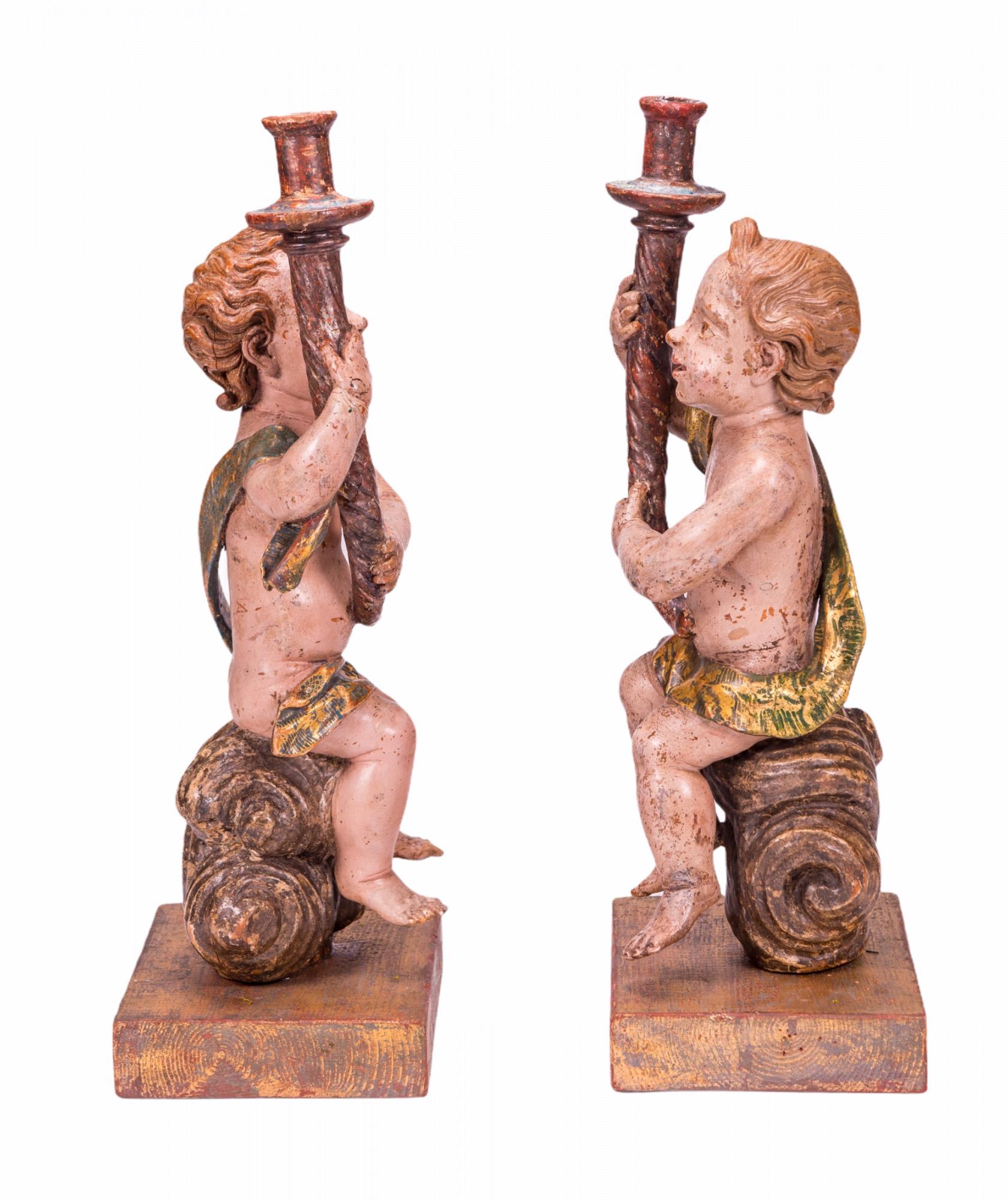 A pair of early 17th Century Baroque polychromed carved wood Angel sculptures with torch shaped candleholders.