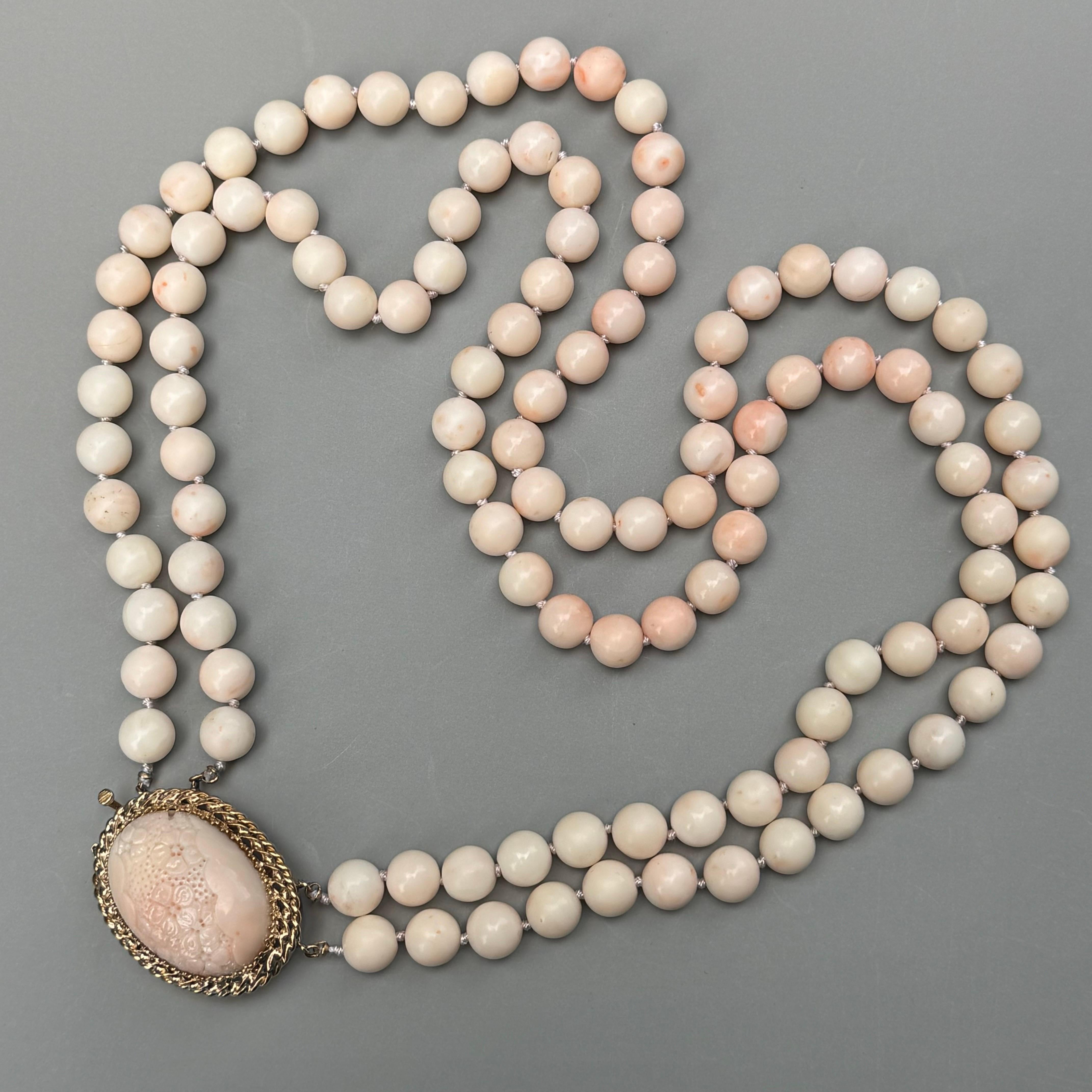 Heavy Vintage hand knotted angel skin coral double strand beaded necklace with a massive carved coral , 14kt gold clasp . Carved floral design coral cab on clasp is set on an raised gold setting with double safety latch . 
Faded 14kt mark and most