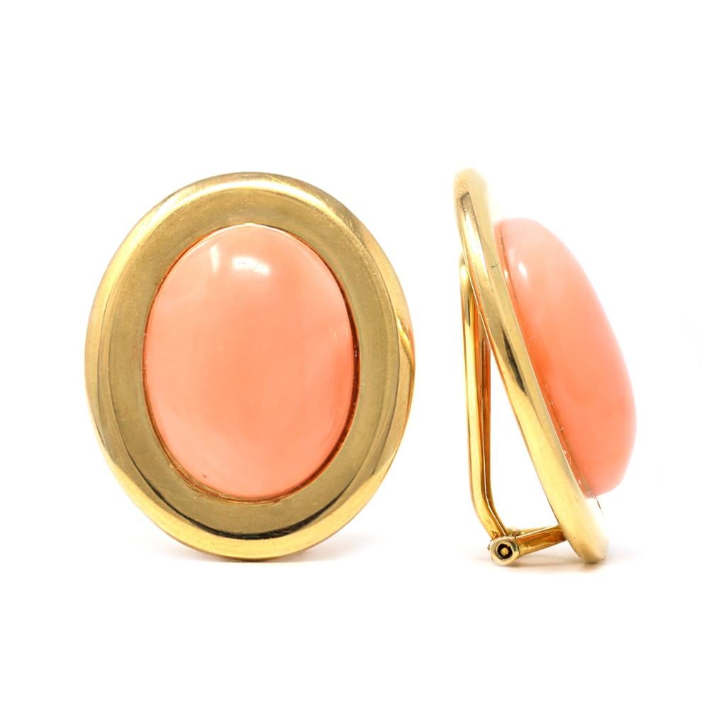 A classic Angel skin coral cabochon ear clips set in 14 karat yellow gold circa 1960. The oval shape coral cabochons are salmony pink with good polish. They are accented by a ring of gold adding substance to the earrings. They measure 0.90” wide and