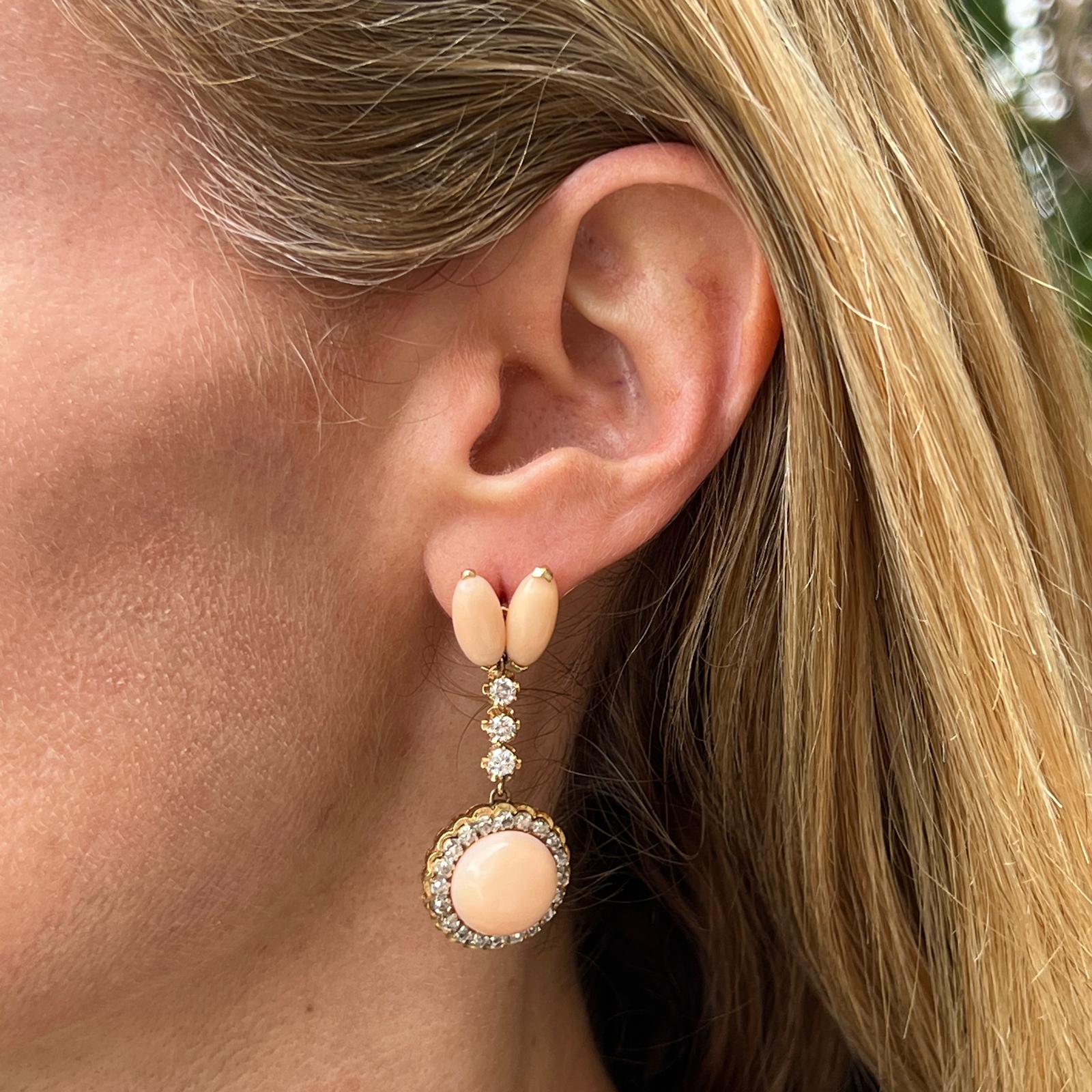 Beautiful coral and diamond vintage drop earrings crafted in 14 karat yellow gold. The earrings feature angel skin coral gemstone and round brilliant and rose cut diamonds. The 96 diamonds weigh approximately 1.00 carat total weight and are graded