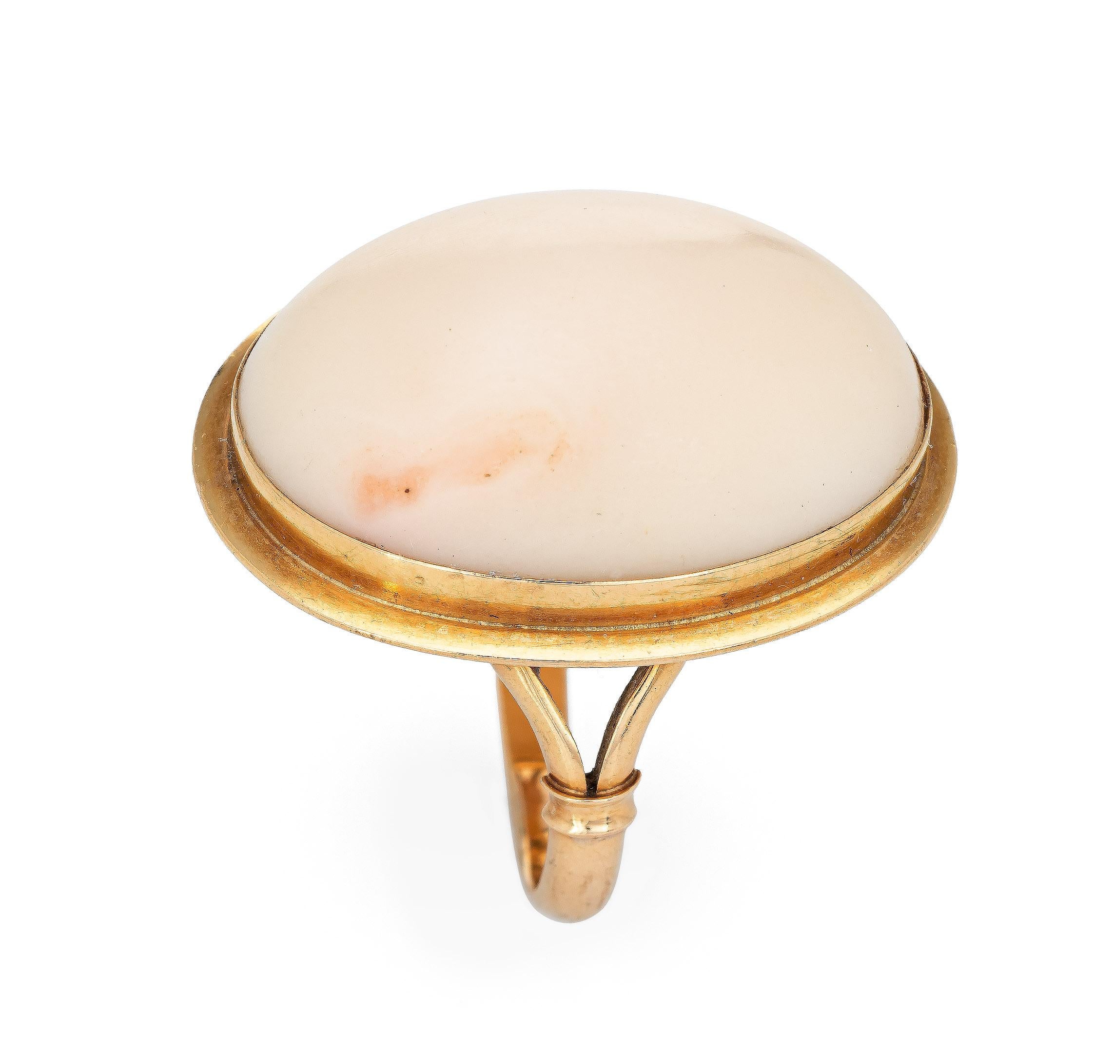 Stylish vintage angel skin coral ring (circa 1950s to 1960s) crafted in 18 karat yellow gold. 

Cabochon cut angel skin coral measures 22mm x 16mm (estimated at 16 carats). The coral is in excellent condition and free of cracks or chips. 

The light