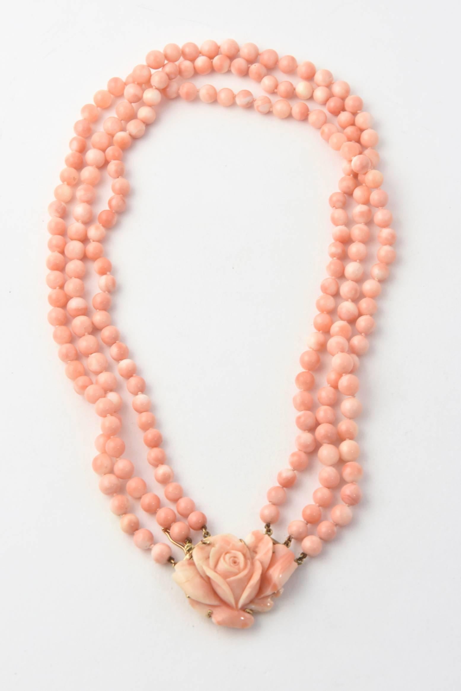 Triple strand of 6mm angle skin coral beads with a carved coral flower & 14k clasp.