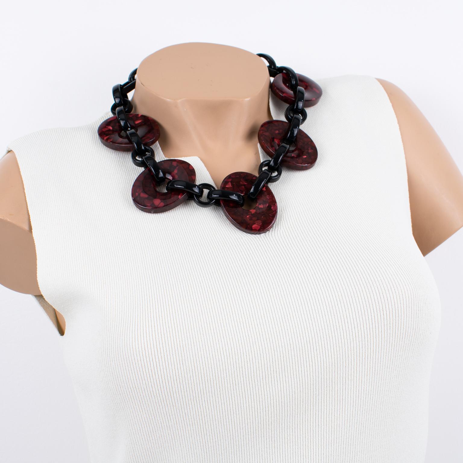 Angela Caputi designed this gorgeous, made-in-Italy acrylic resin or lucite choker necklace. The around-the-neck shape boasts a thick black resin chain contrasted with oval donuts in burgundy-red marble. The piece has the original brand signature