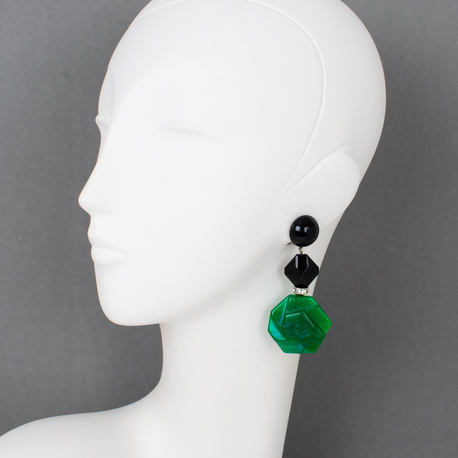 These very chic Angela Caputi, made-in-Italy resin clip-on earrings feature a dangling shape with black color contrasted with emerald green marble resin geometric pebble beads and complimented with crystal rhinestone spacers. Her matching colors are