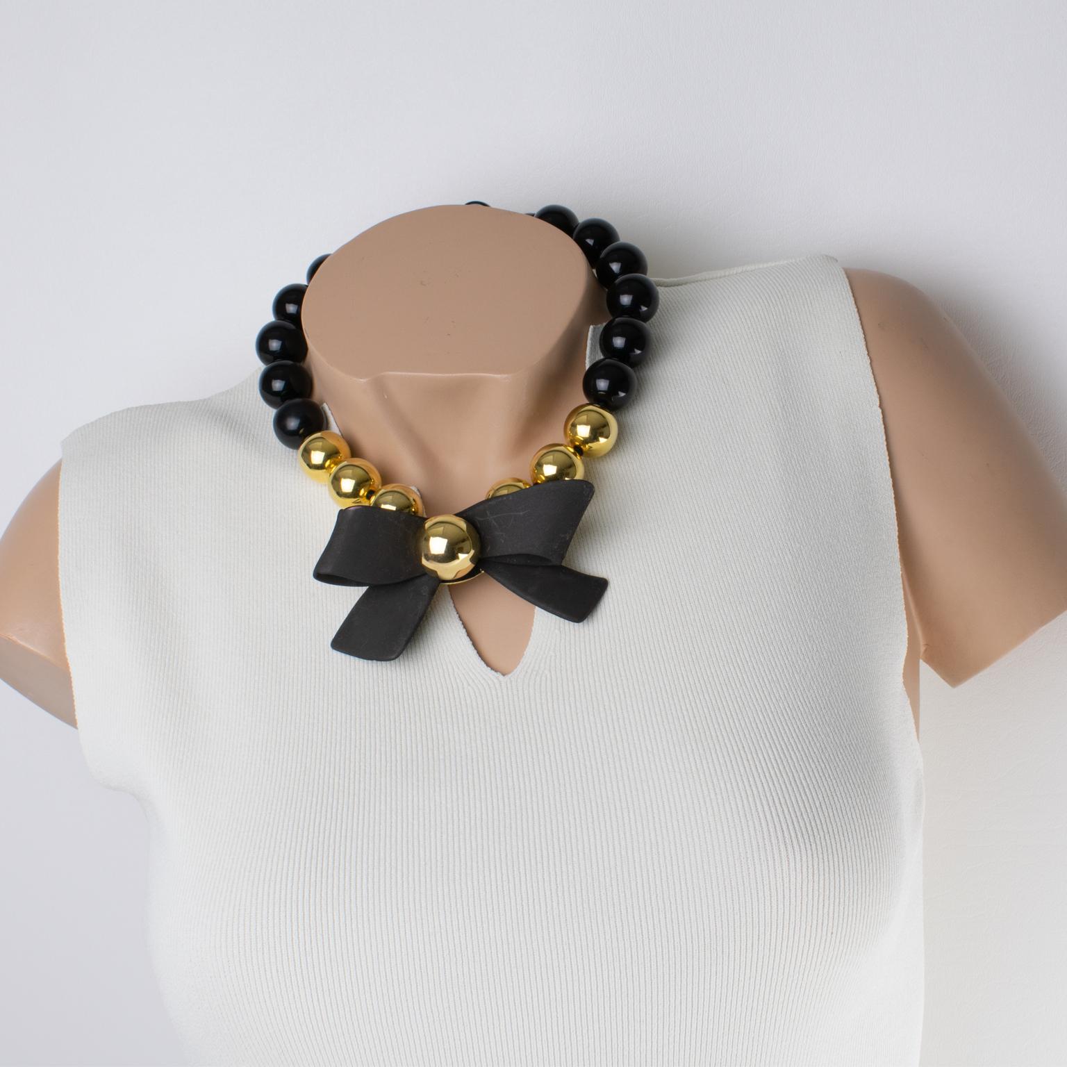 This stunning Angela Caputi, made in Italy, choker necklace features large resin beads with an oversized dimensional bow pendant. The necklace has an elegant black contrasted with gold composition, and the large bow has a black mat finish. Her