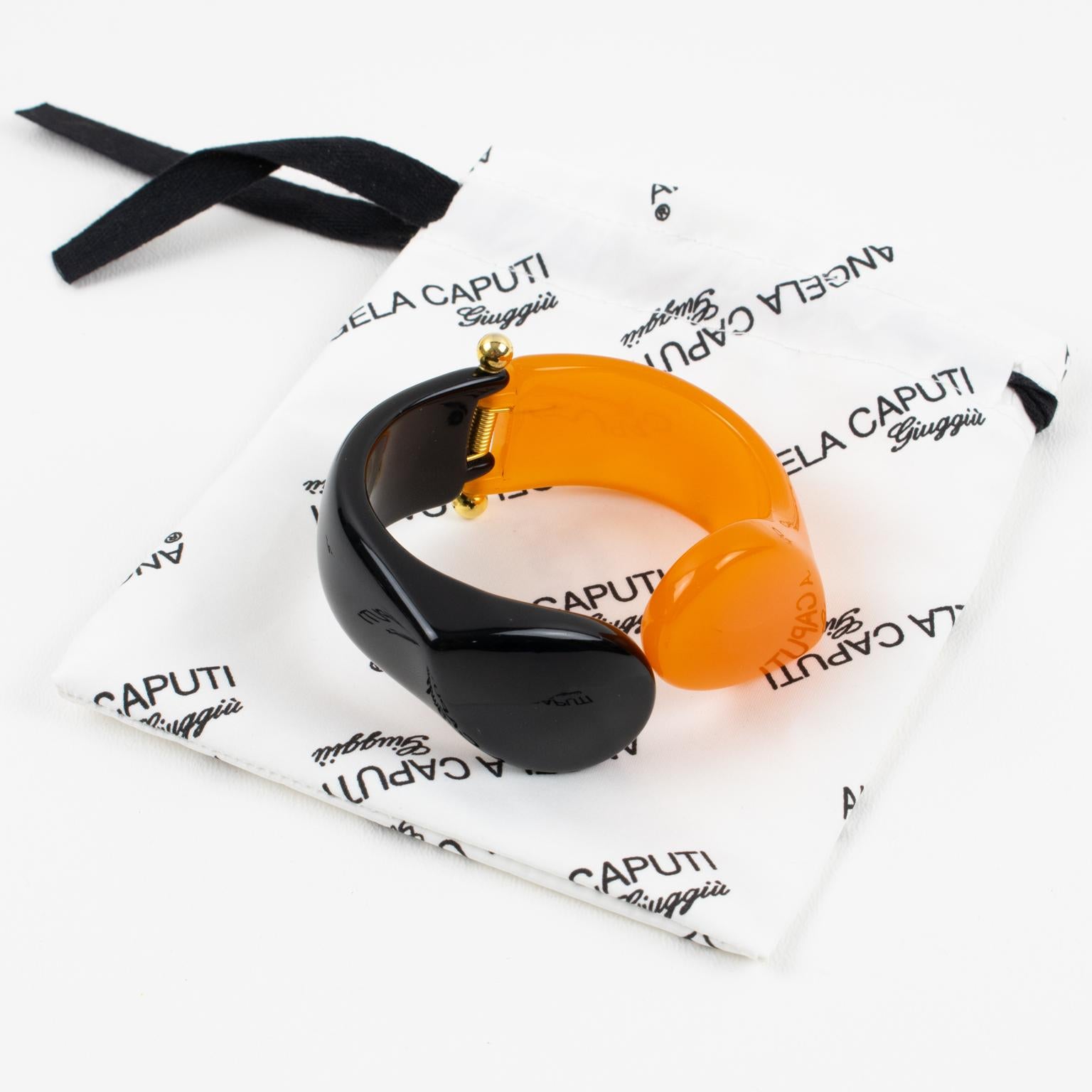 This gorgeous Italian designer Angela Caputi resin clamper bracelet features a contrasting black and orange shape with a carved geometric design. The gilded metal hardware hinge is in excellent working condition.
As you know, Caputi jewelry is not