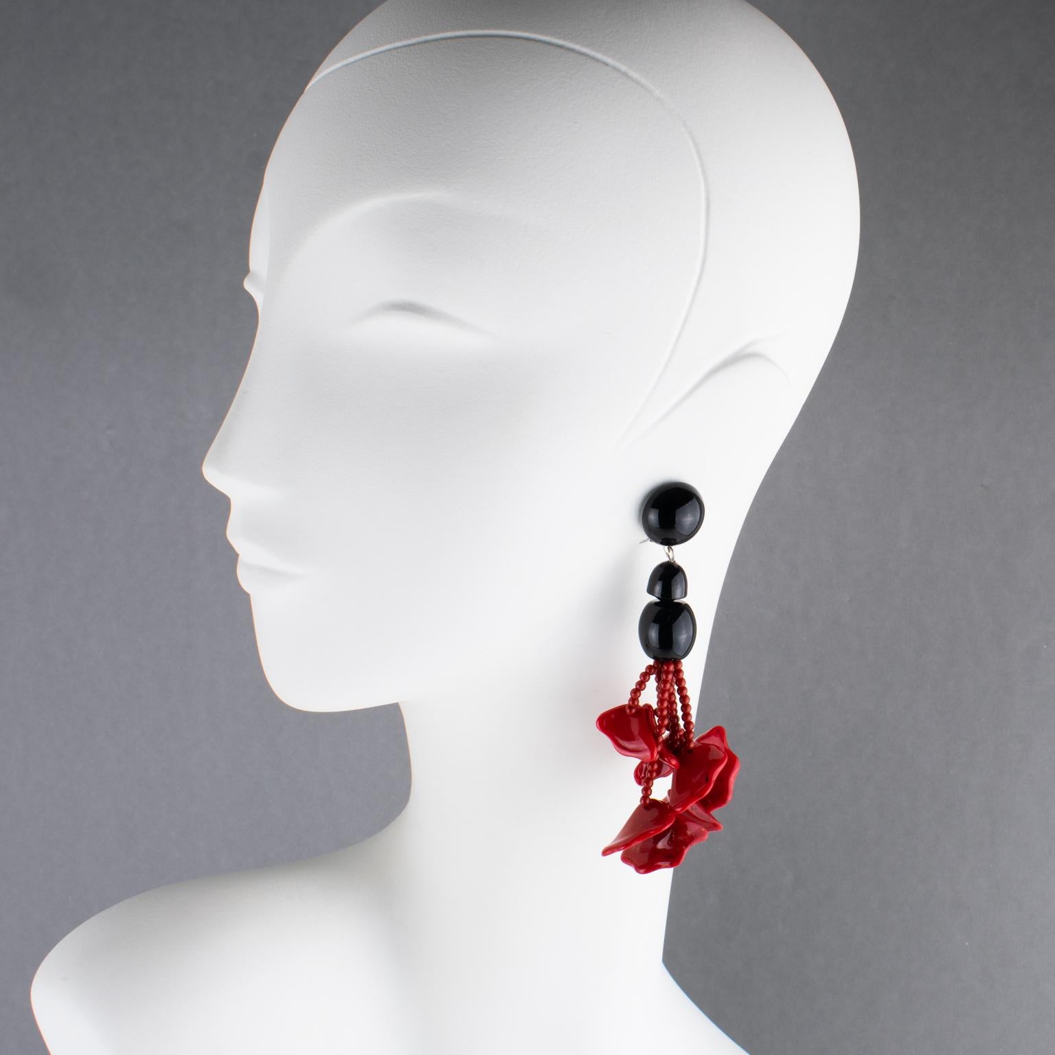 Angela Caputi, Italie, a conçu ces superbes boucles d'oreilles à clip en résine. Elles présentent un design pendentif surdimensionné avec des éléments de couleur rouge cinabre et noir. Perles de rocaille et pétales ondulés et façonnés dans des