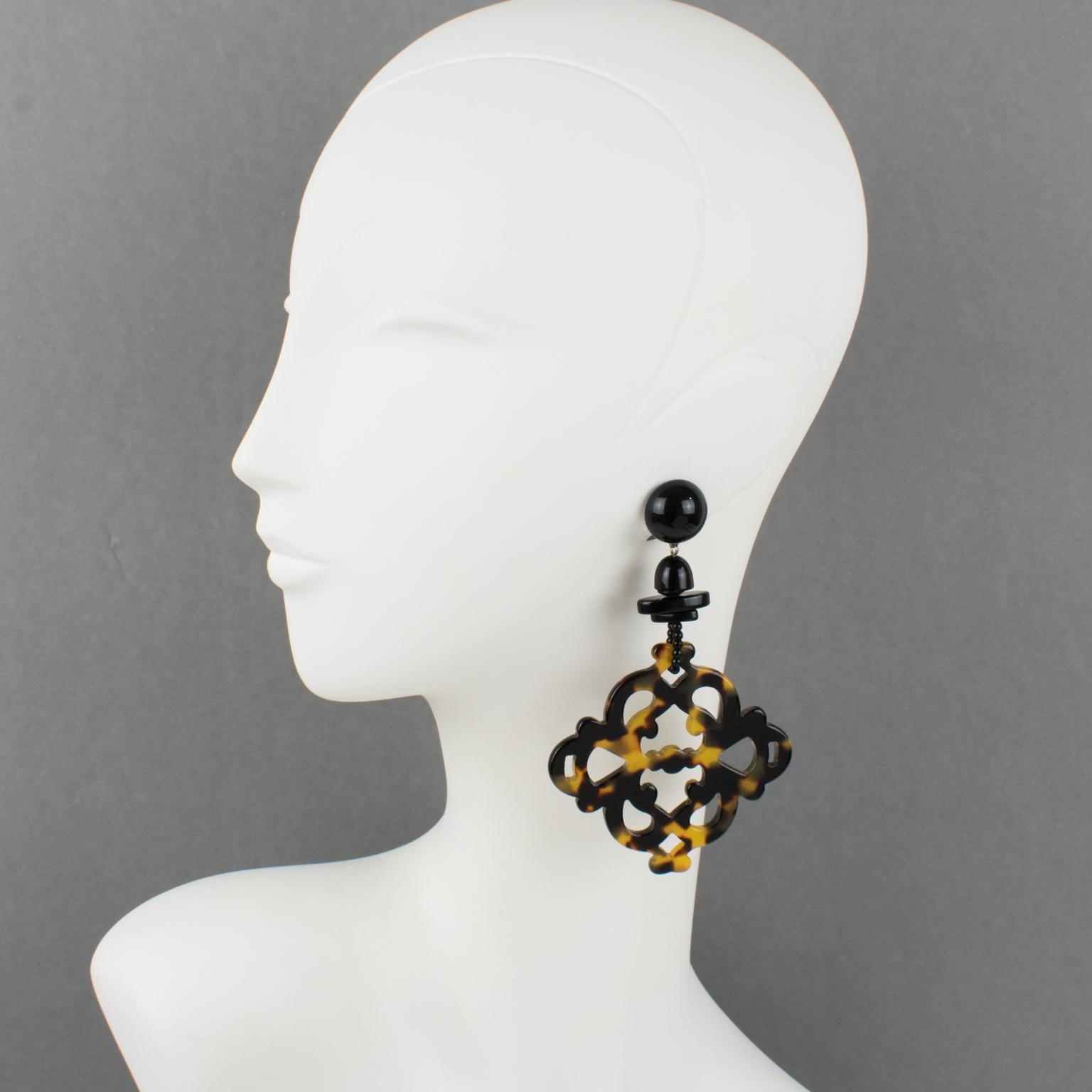 These sophisticated Angela Caputi, made in Italy resin clip-on earrings feature a chandelier dangling shape with black resin geometric links contrasted with carved and see-thru large elements in a textured tortoiseshell pattern. Her matching of