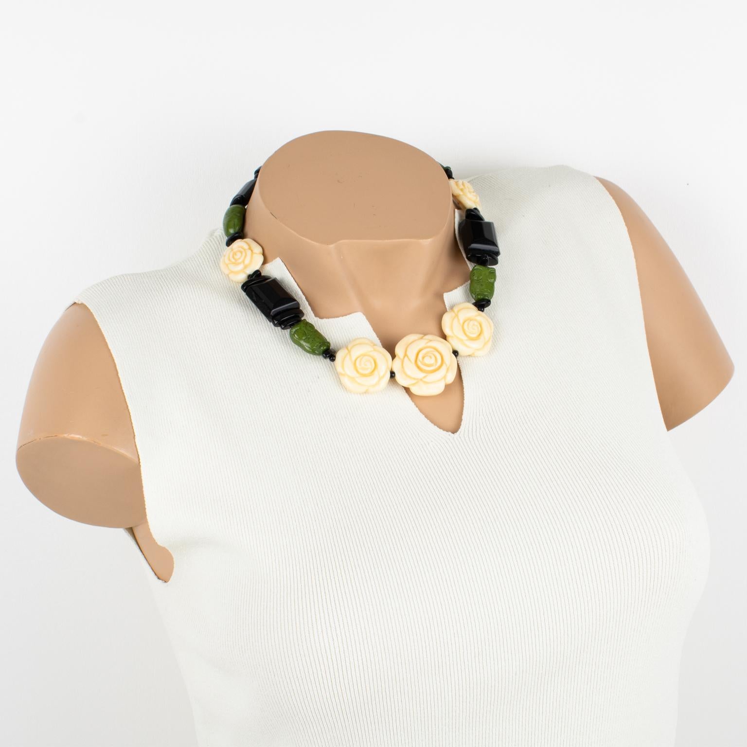 Angela Caputi designed this lovely resin choker necklace. This necklace features carved beads with flower and owl shapes and geometric pebble elements. The choker boasts black with green colors and ivory-like color contrast. Her color combination is