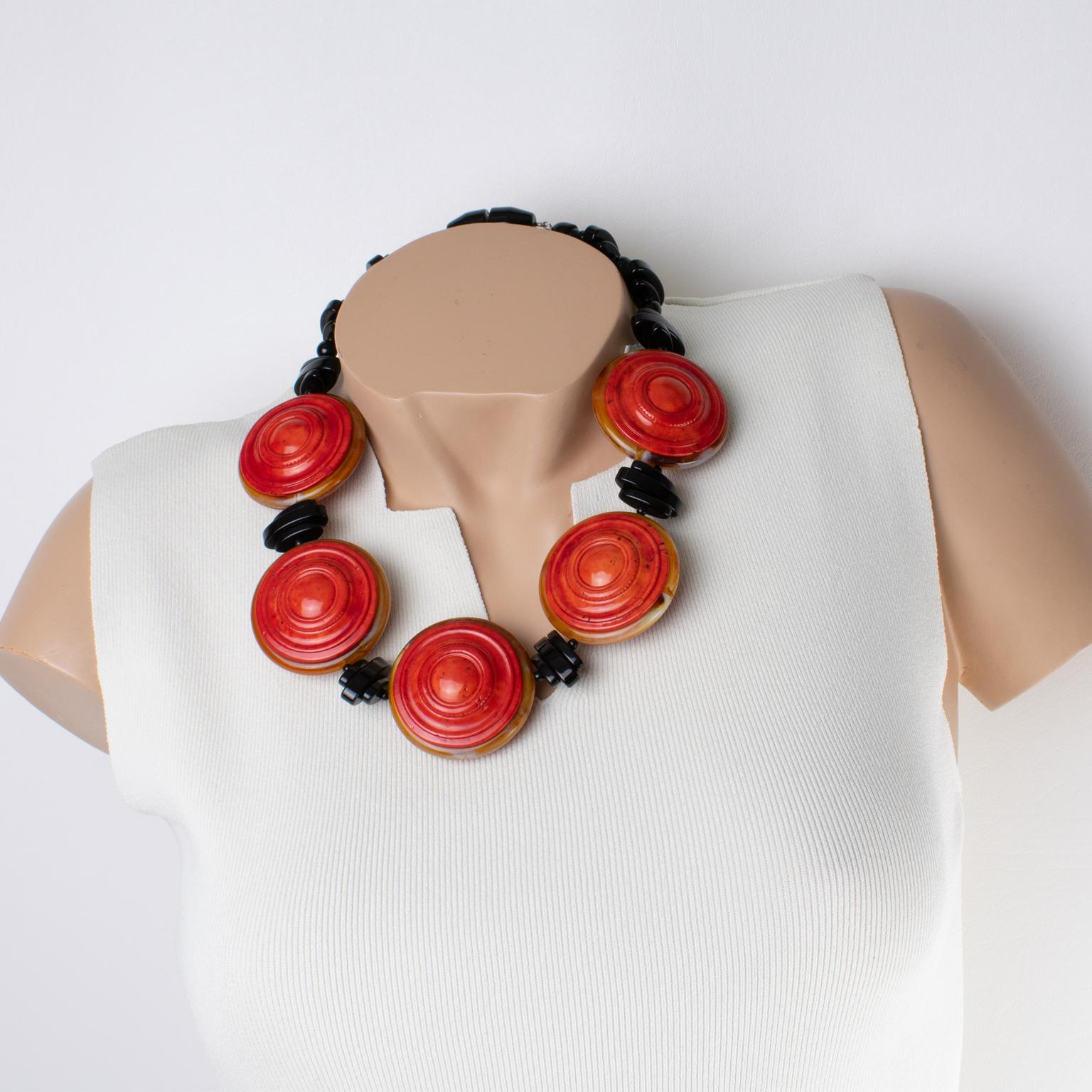 Angela Caputi ha disegnato questa favolosa collana in resina in Italia. La forma del girocollo vanta elementi geometrici in resina nera in contrasto con dischi rotondi intagliati a cinque dimensioni nei colori rosso cinabro e ambra miele. Il pezzo