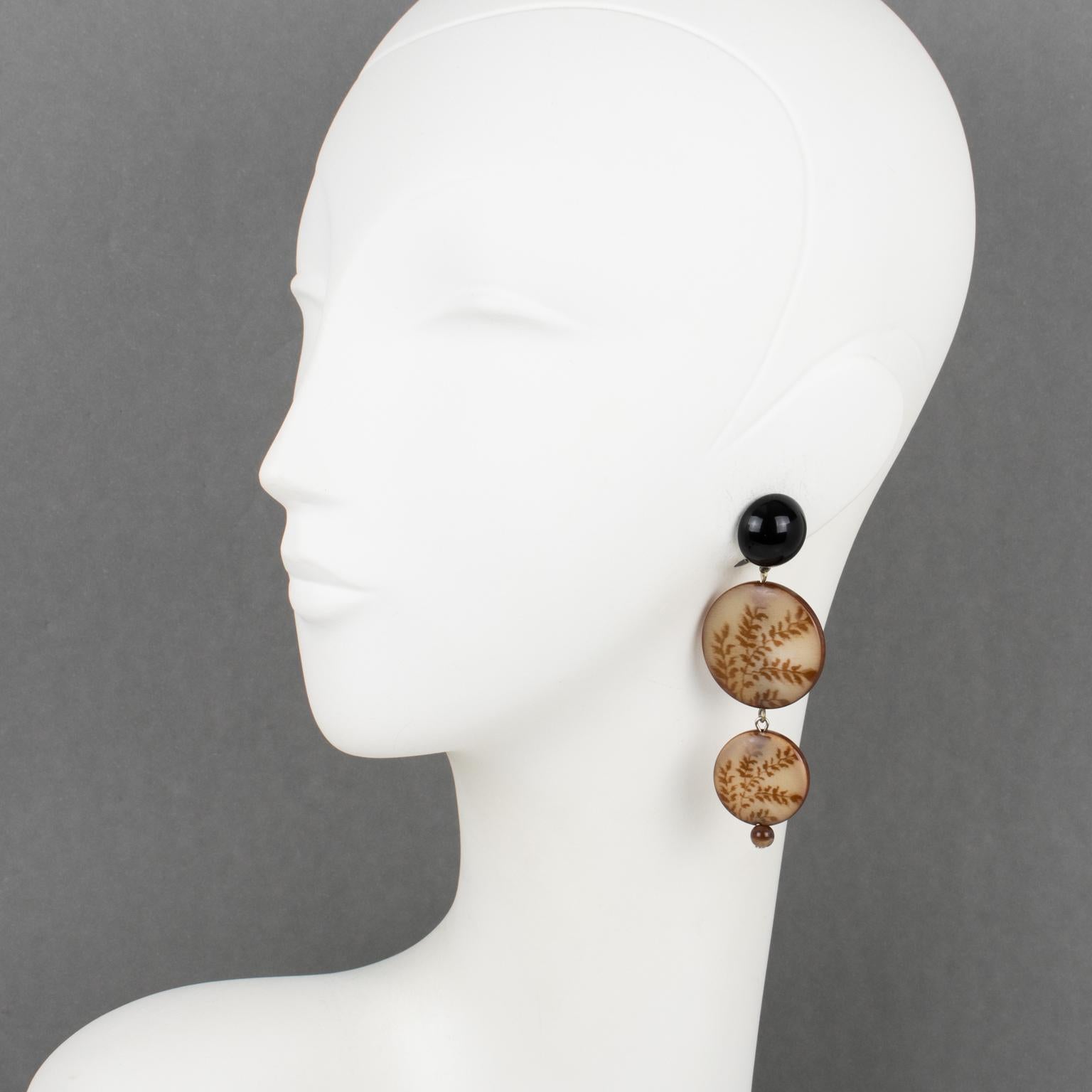 Angela Caputi designed these sophisticated made-in-Italy dangle clip-on earrings. The pieces boast a black contrast with brown, tawny color. The dimensional dangling graduated disks have fern design engraving that works like a photo negative. 
As