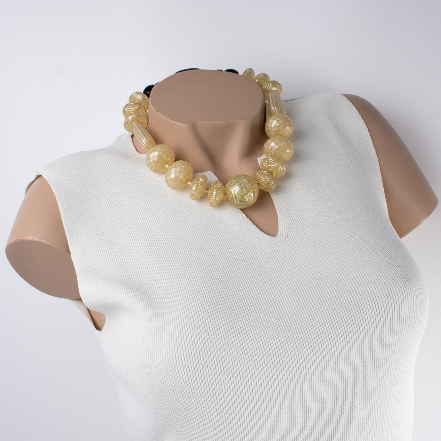 Angela Caputi ha diseñado este impresionante collar de cuentas hecho en Italia. La gargantilla presenta una forma de una sola hebra construida con grandes cuentas de resina tallada en un tono amarillo champán claro con un dibujo perlado y