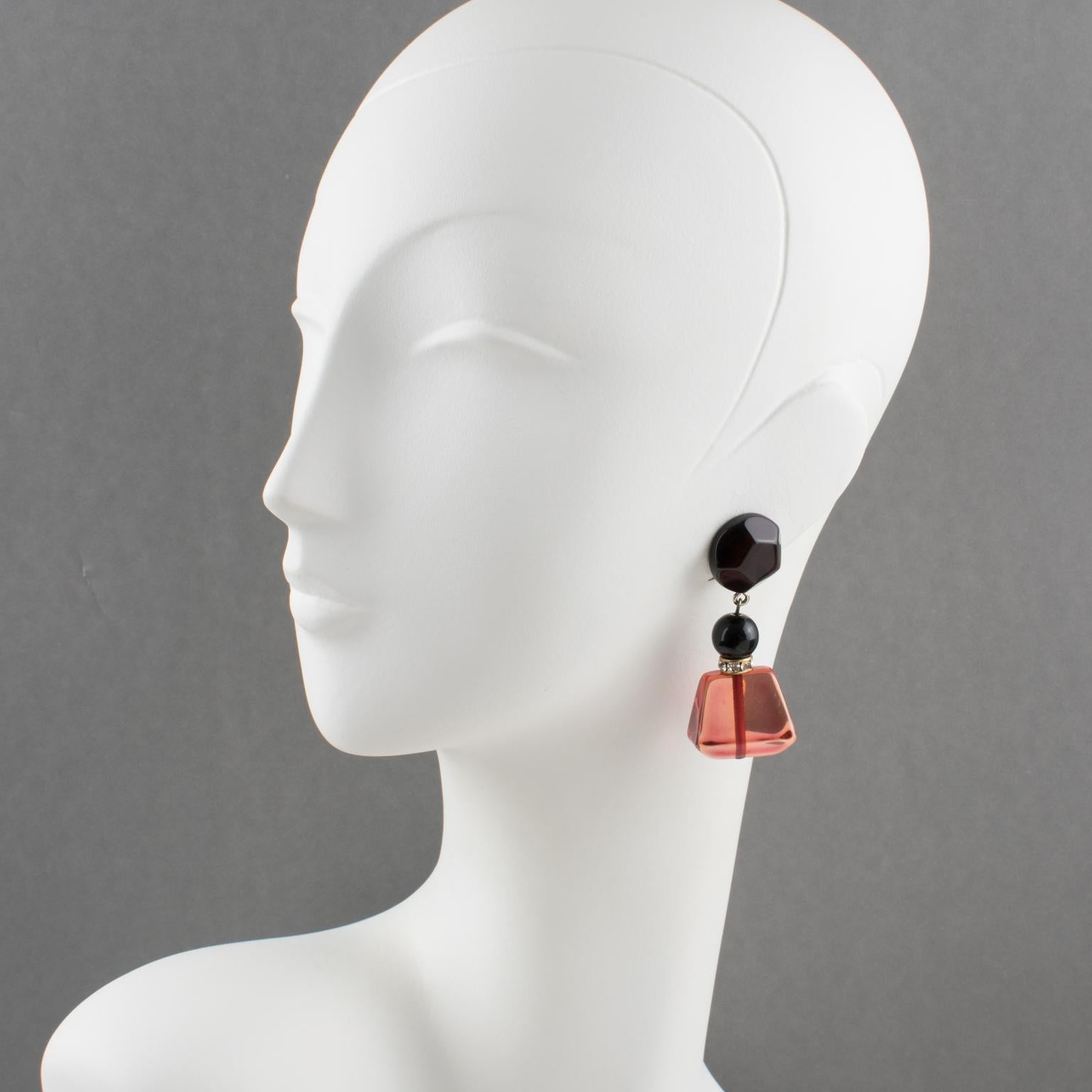 Beautiful Angela Caputi, made in Italy resin clip-on earrings. Dangling shape with black color contrasted with large transparent cranberry red resin geometric pebble bead and compliment with a tiny clear rhinestones spacer ring.
As you know Caputi