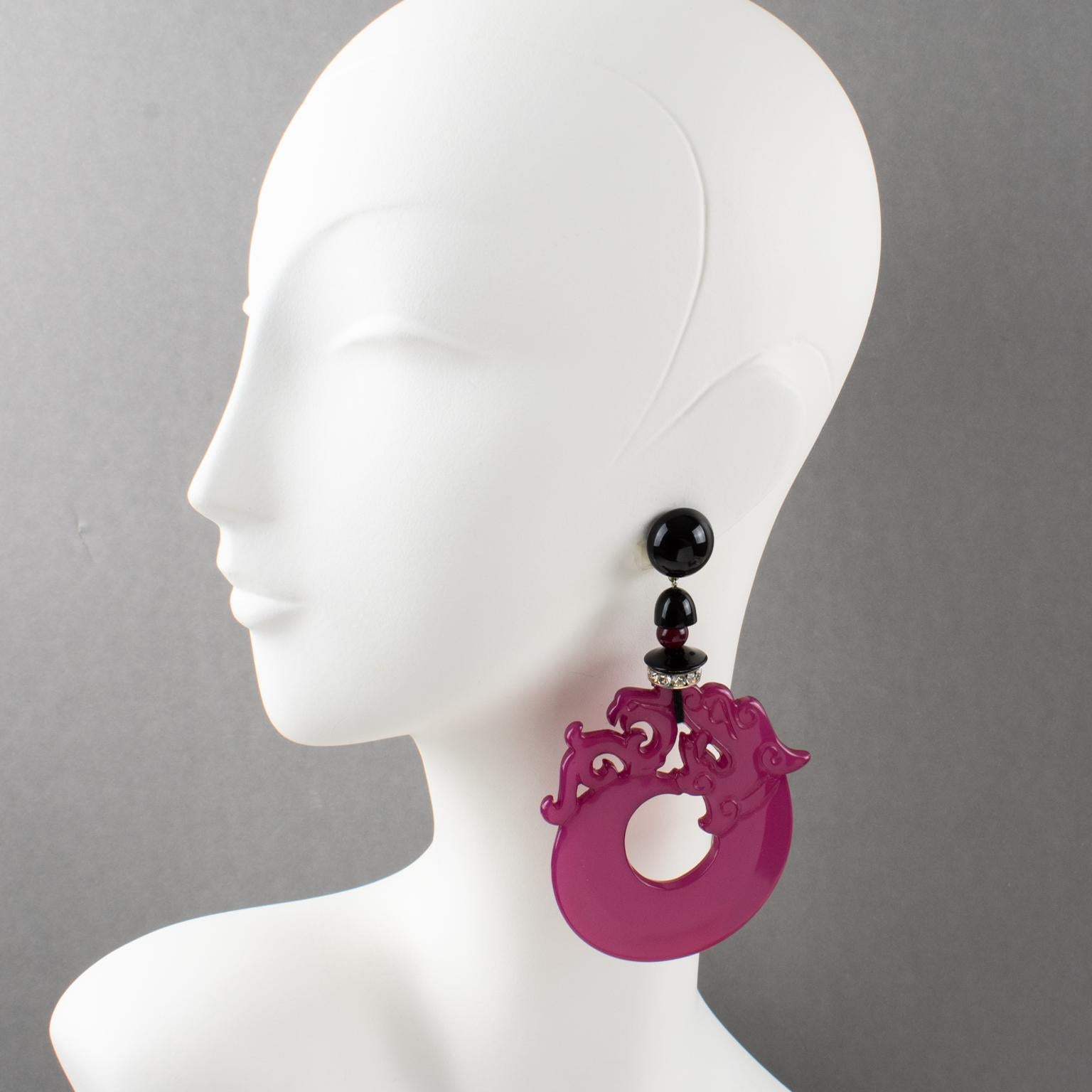 Impressive oversized Angela Caputi, Italy dangling clip-on earrings. Dimensional statement shape working on black color contrasted with magenta purple and crystal rhinestones spacer ring. A huge resin dragon-shaped element builds in an extra-large