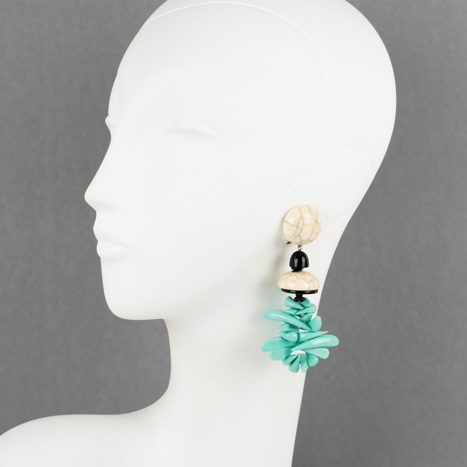 These stunning Angela Caputi, made-in-Italy resin clip-on earrings feature a massive dangling shape with faux marble elements complemented with faux turquoise stick beads and contrasted with black spacers. Her color matching is always extremely
