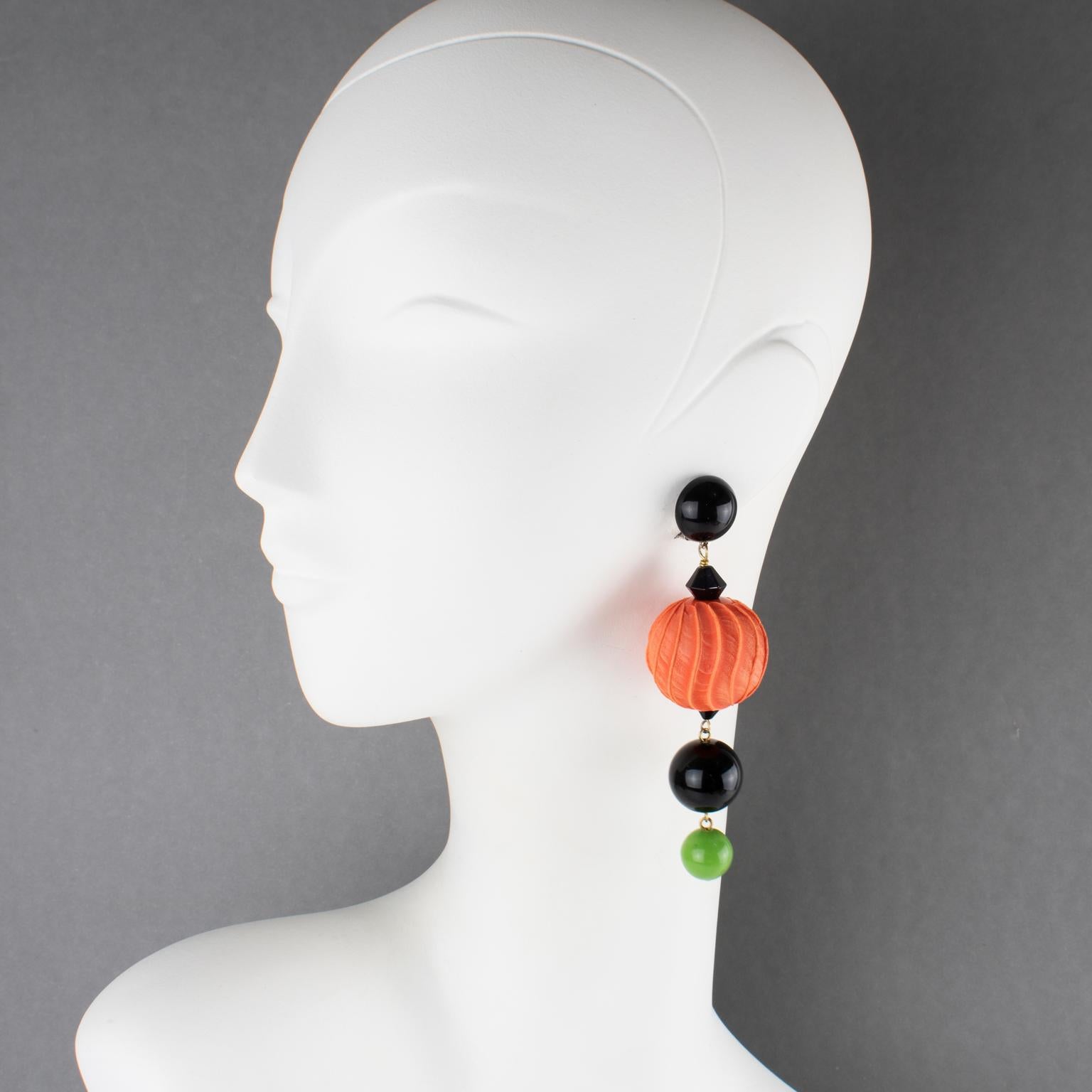 Ces superbes boucles d'oreilles à clip en résine Angela Caputi, fabriquées en Italie, présentent une forme pendante avec une perle géante sculptée et texturée en forme de citrouille, contrastée par des éléments noirs et verts. Ses couleurs sont