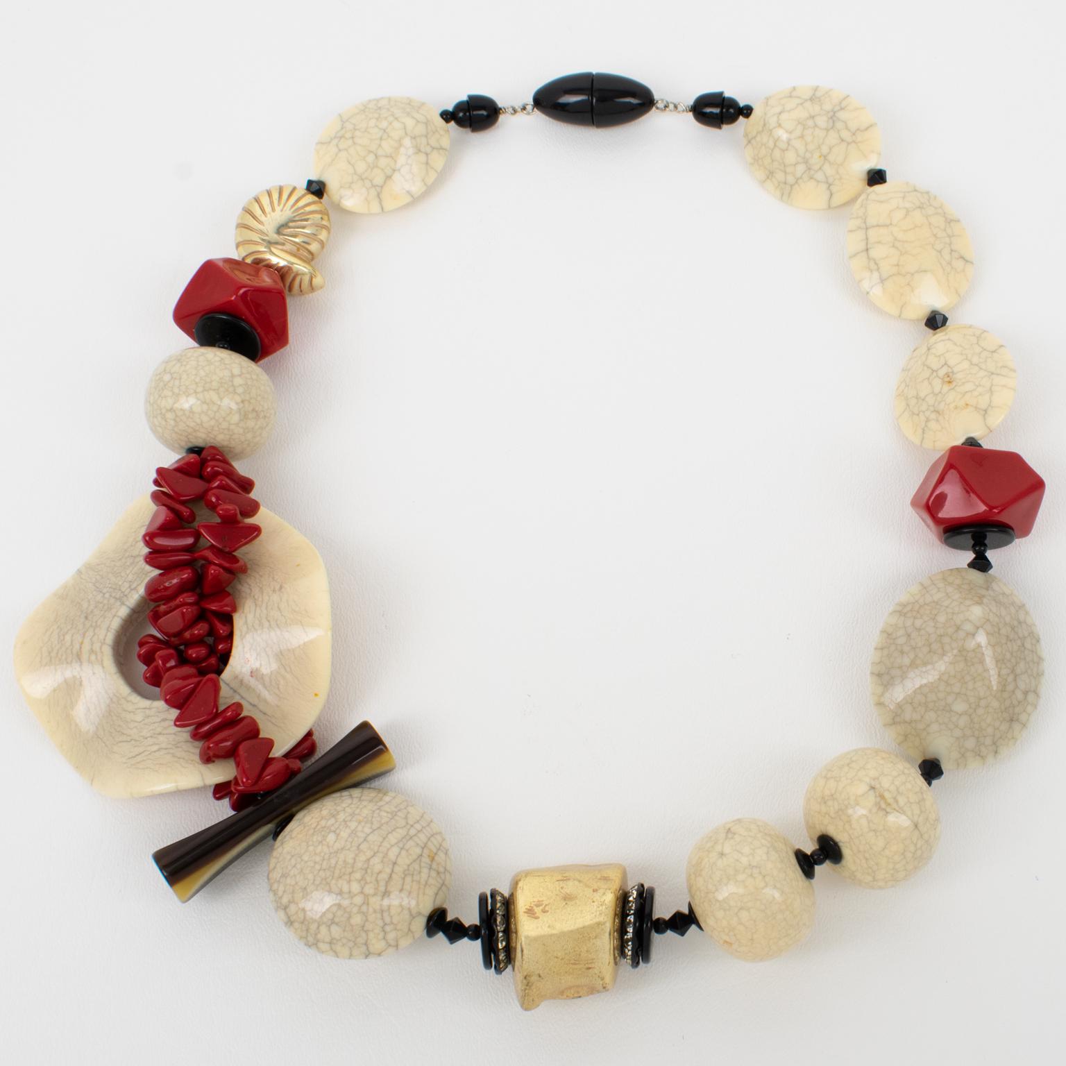 This impressive Angela Caputi, made-in-Italy resin necklace features a sculptural Japanese-inspired oversized design. The piece is built with faux-ceramic beads in an off-white marble color complimented with faux red Cinnabar elements and ornates