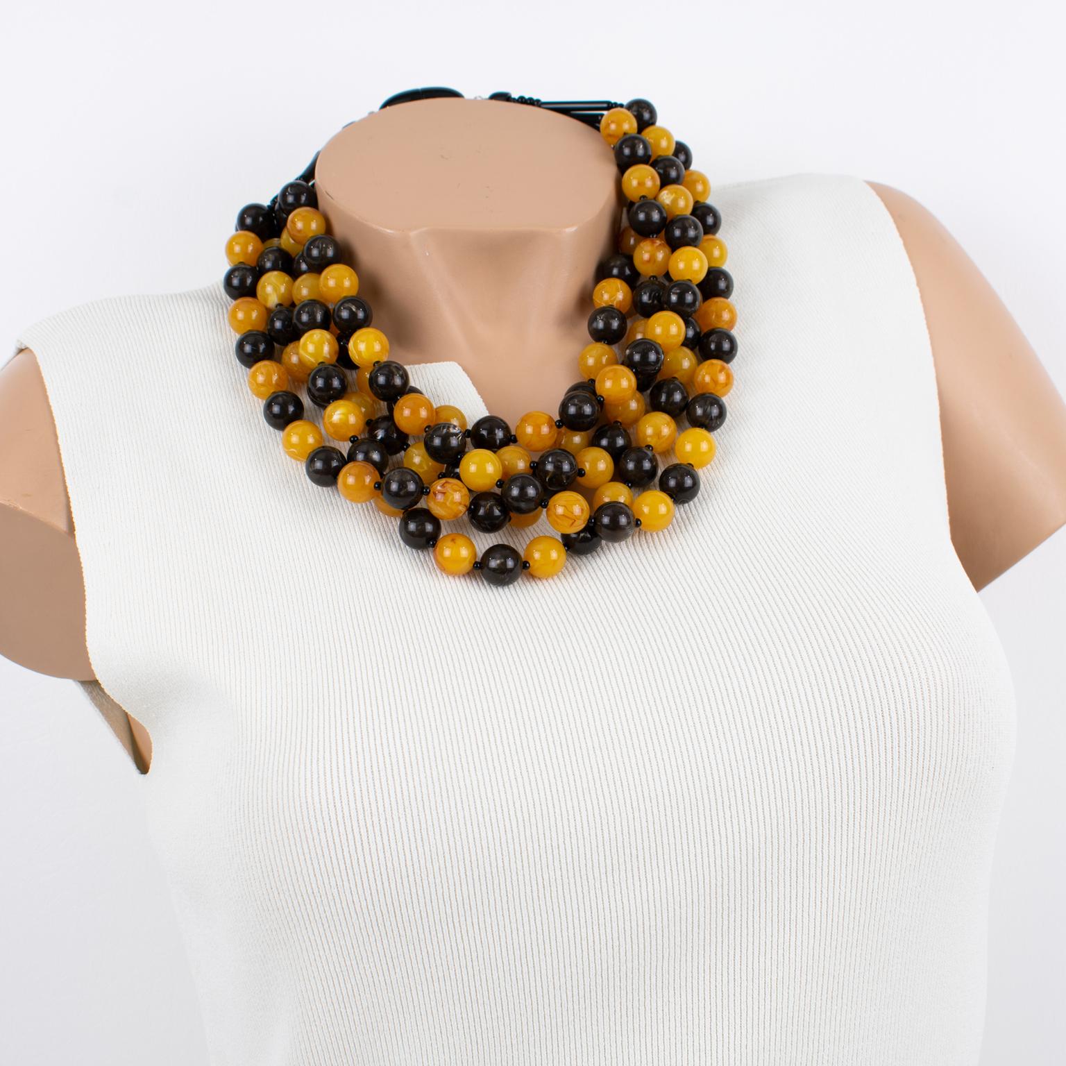 Questa affascinante collana di Angela Caputi con perline in resina, realizzata in Italia, presenta un design a più fili di macedonia con perline di semi d'uva nei colori nero e arancione mandarino. I suoi abbinamenti di colore sono sempre di gran
