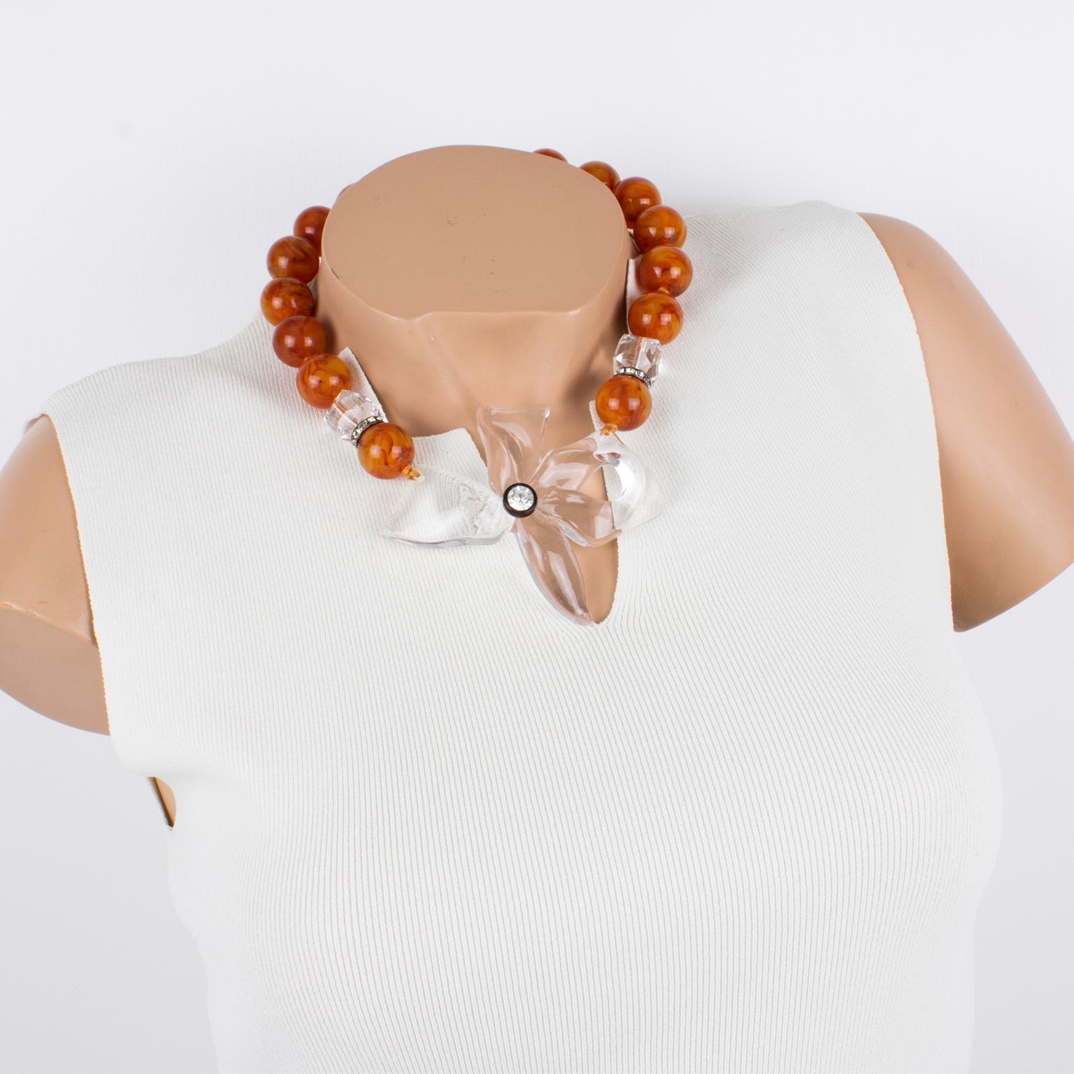 Angela Caputi ha creado este elegante collar gargantilla de resina fabricado en Italia. Esta pieza funciona con cuentas de color mármol ámbar de té rojo que contrastan con un colgante de flor tallada transparente maciza, cuentas facetadas y