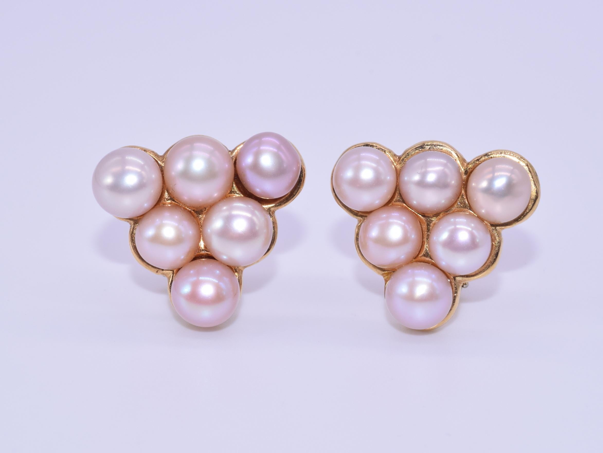 A pair of triangular clip earrings are adorned with cultured pink pearls mounted in 18 karat yellow gold, signed Cummings, 1995.