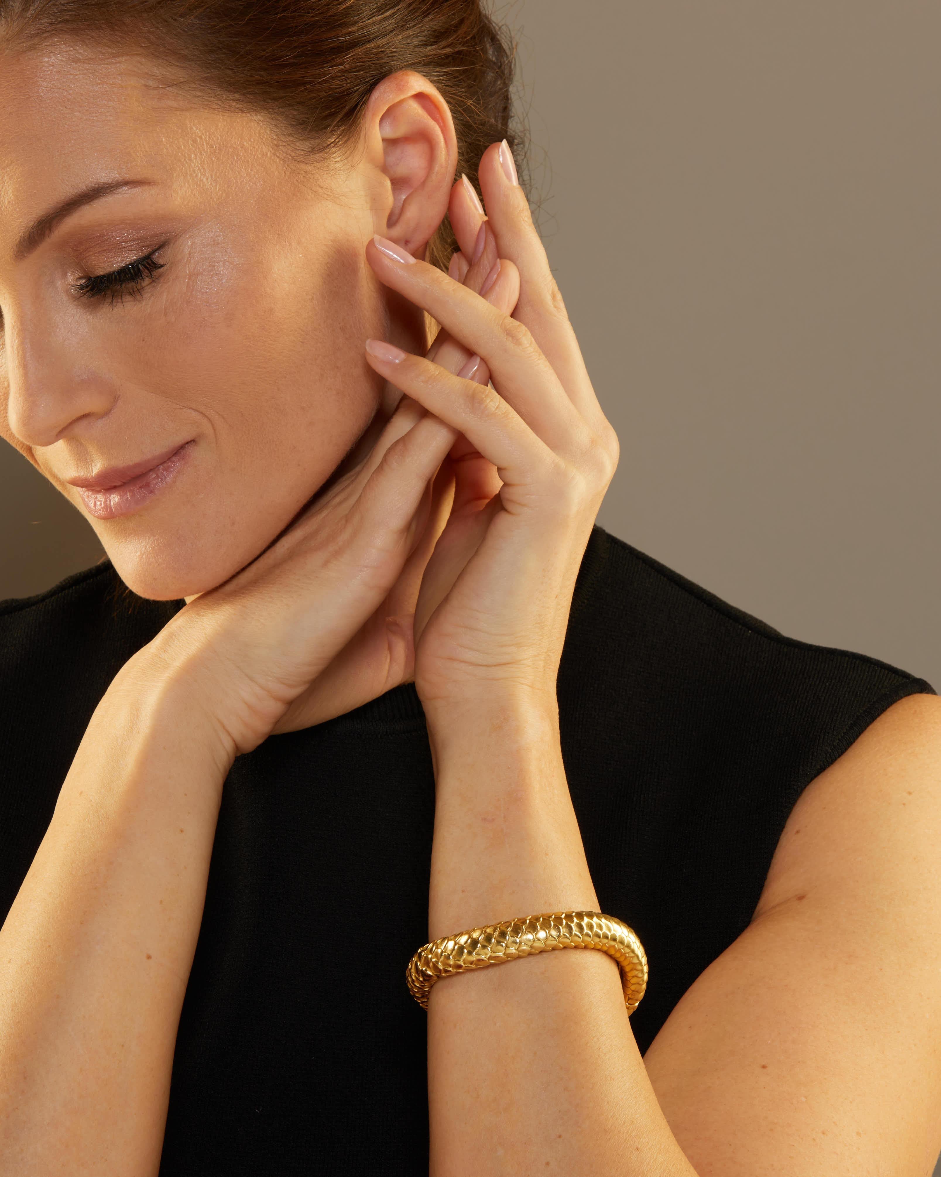 Angela Cummings is drawn to the inherent patterns and forms of nature. This substantial gold bangle curves gracefully around the wrist and features an abstracted scale design in a smooth satin finish. 

The piece secures with a push in clasp and