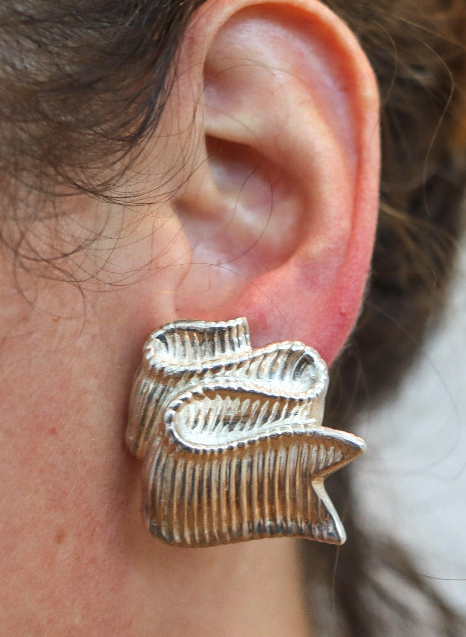 Twisted ribbons clips earrings designed by Angela Cummings.

This is a beautiful pair of clips-on created by Angela Cummings at her own silversmith studio in New York City, back in the 1985. These earrings have been designed as a folded textured