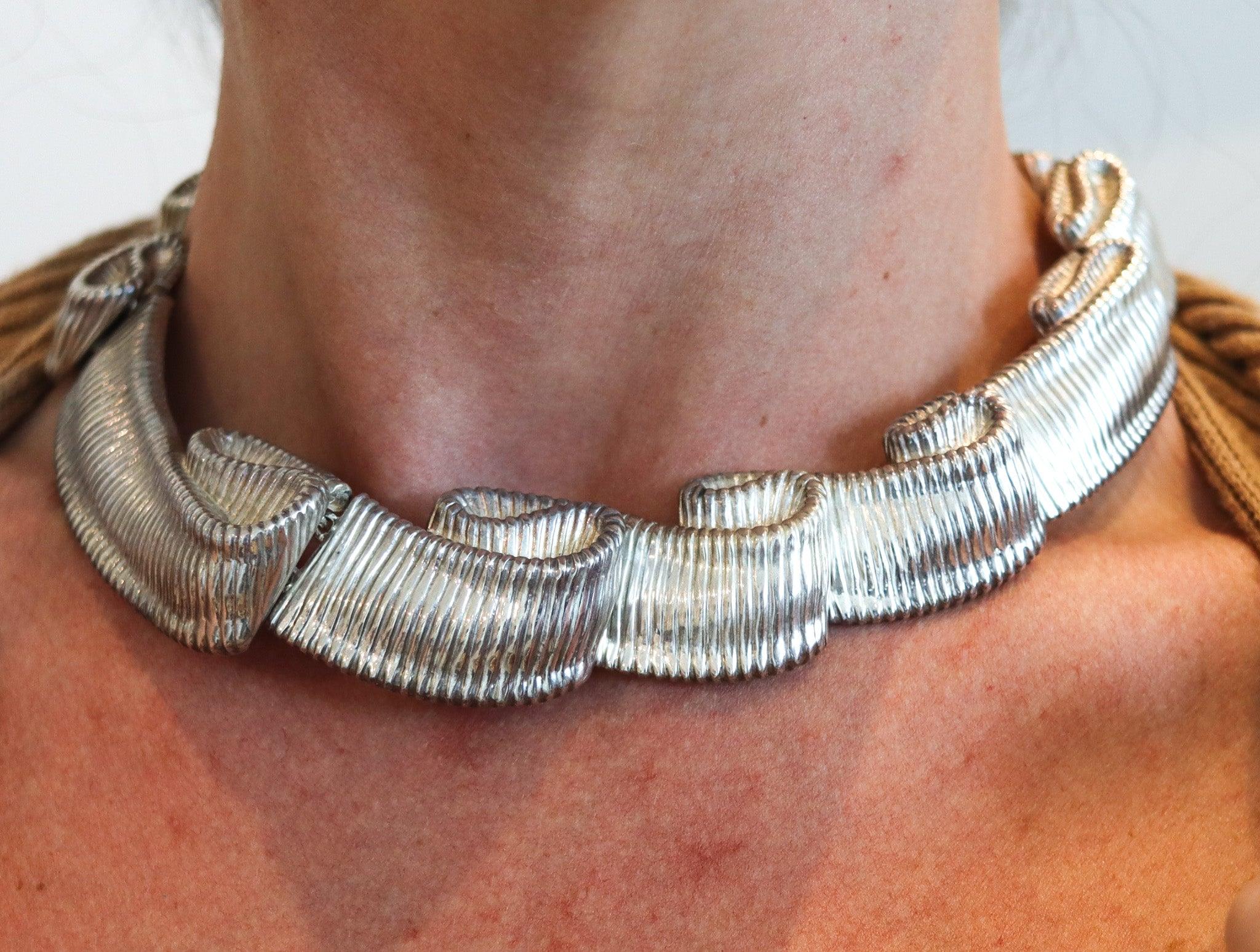 Twisted ribbon necklace designed by Angela Cummings.

This is a gorgeous necklace created by Angela Cummings at her own silversmith studio in New York City, back in the 1985. This flexible necklace has been designed as a folded textured ribbon