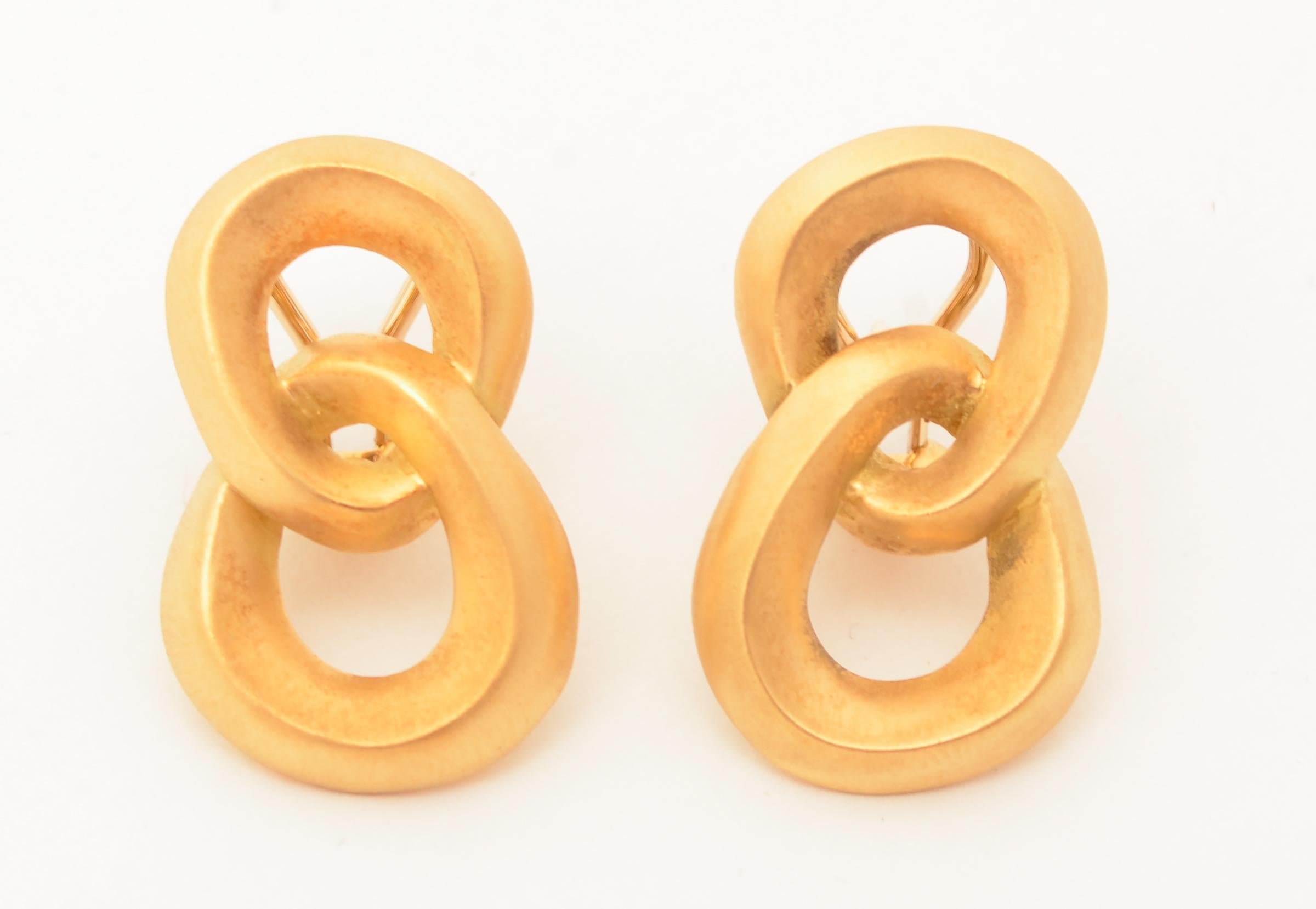 Double loop earrings by Angela Cummings in 18 karat gold with a matte finish. The irregularly shaped, intertwining hoops are of slightly different sizes with the bottom a hair larger than the top.
Omega backs; dated 1986.
Angela Cummings began