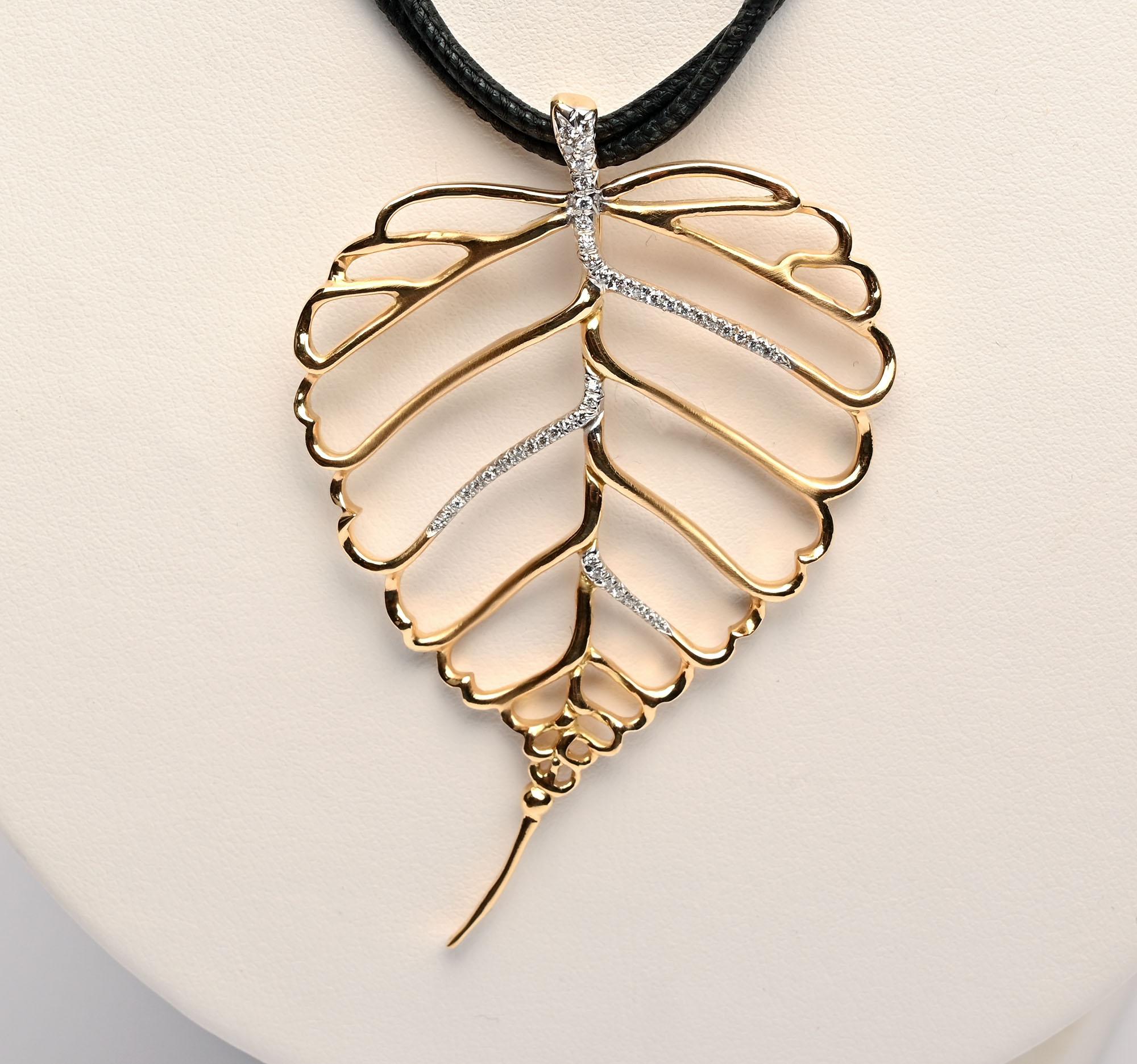 Streamlind pendant necklace of 18 karat gold with diamonds along the veins and stem of the leaf. Angela Cummings often worked with Salvador Assael. Both of their names are stamped on this piece. The pendant is on a double leather cord that measures